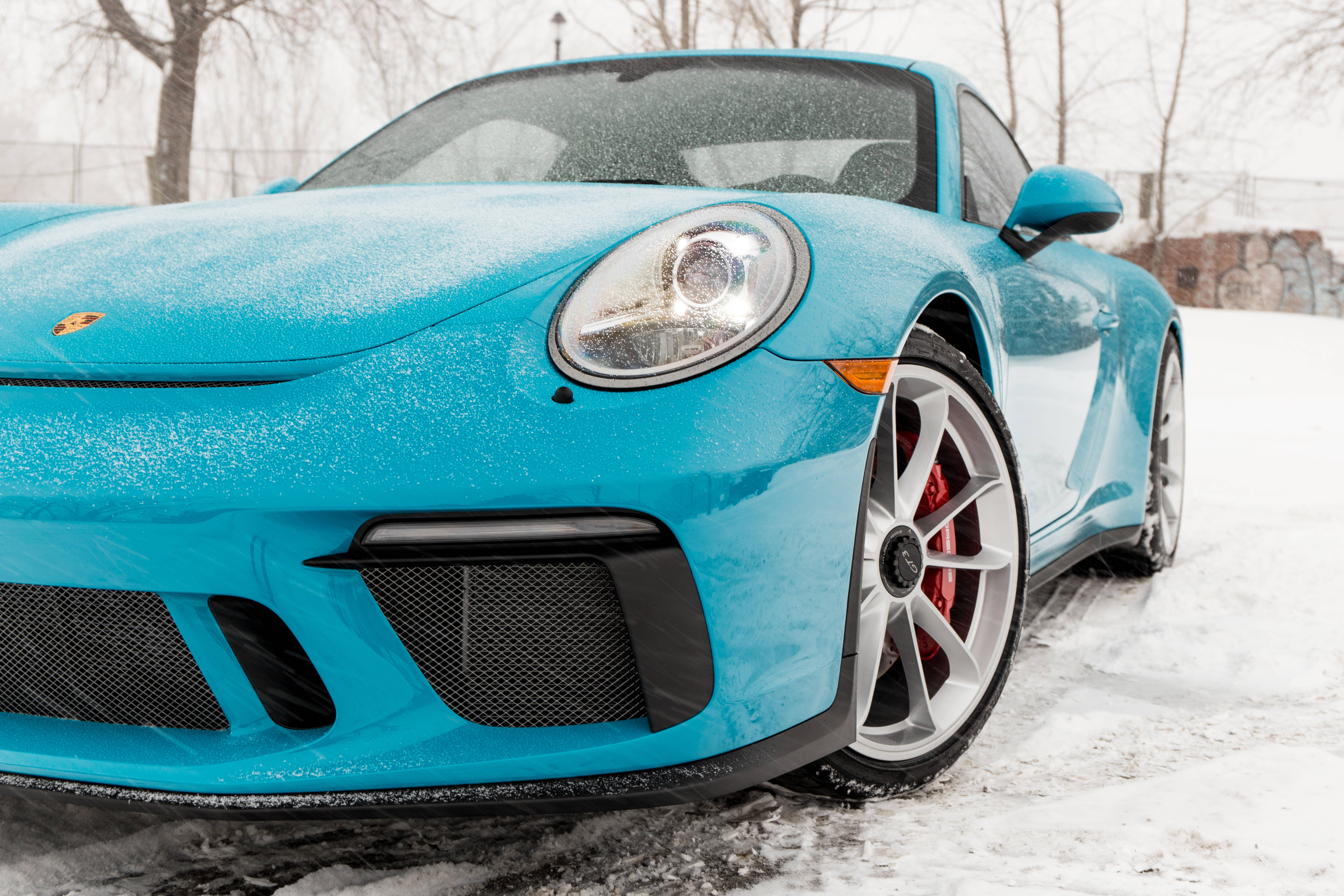 車輪上的王者：保時捷911 GT3豪華跑車 壁紙 — 一輛鮮豔的藍綠色保時捷911 GT3停在剛下的雪中，引擎蓋和車輪上結滿霜。