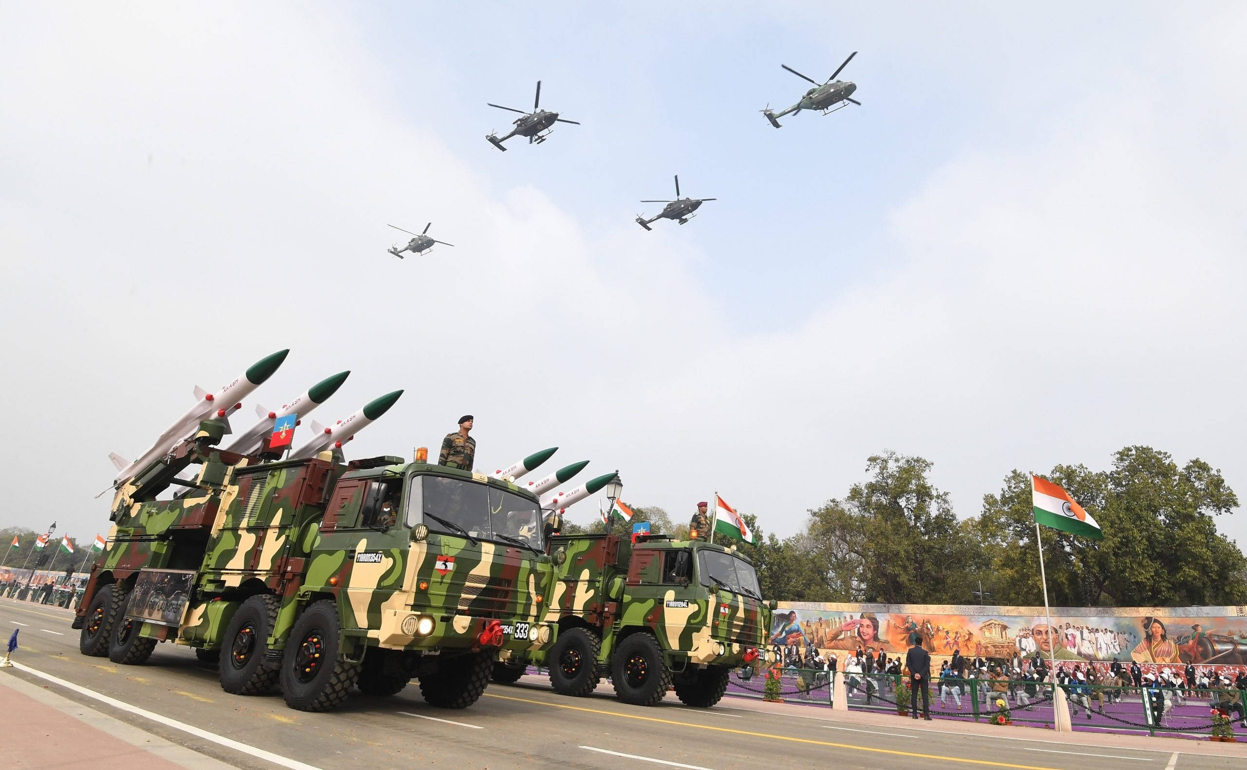 Indian Army 桌布 壁紙 — 軍用卡車載著導彈在街上遊行，直升機在頭頂飛過，慶祝國慶。