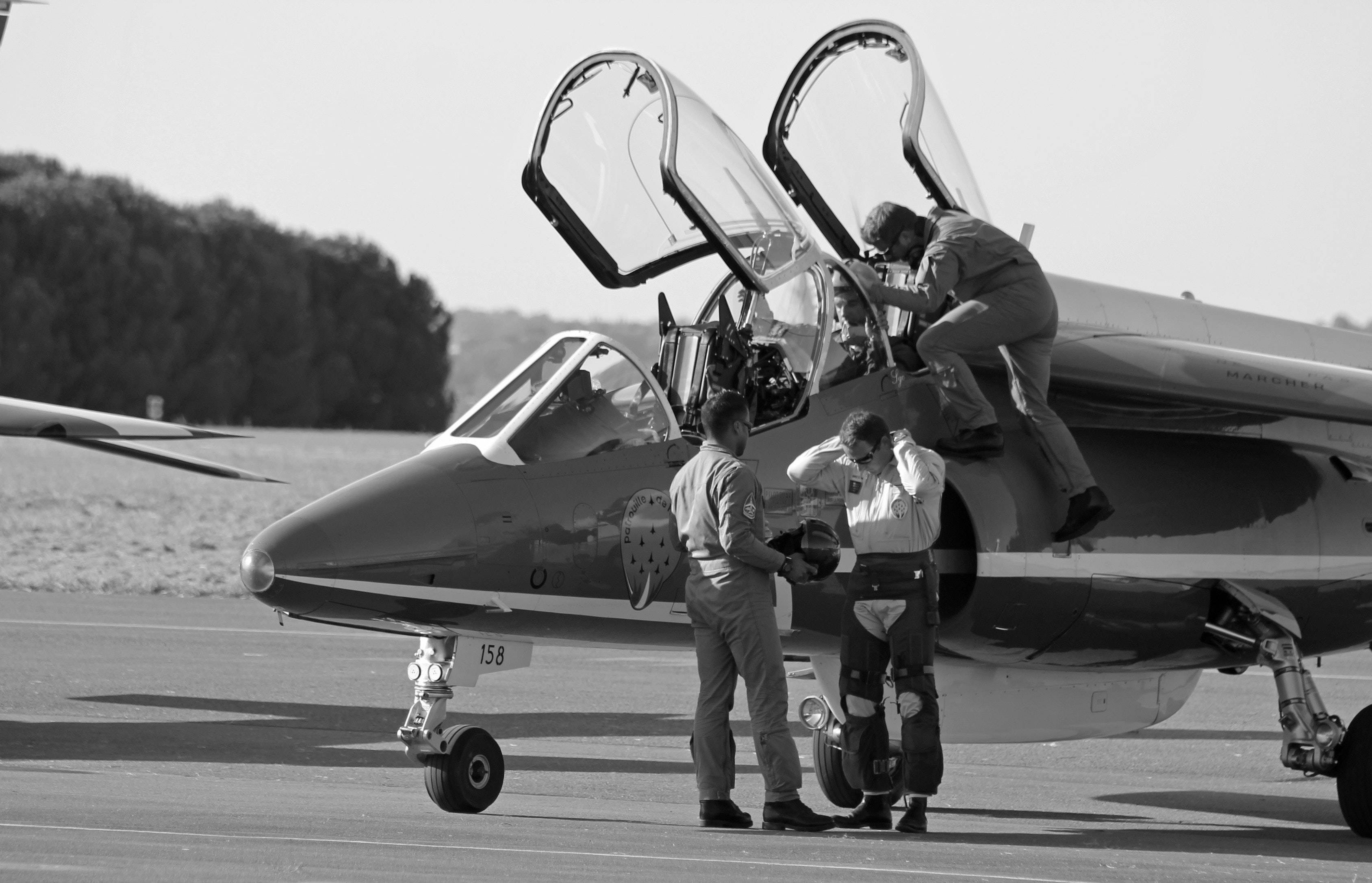Fighter Plane 桌布 壁紙 — 軍用噴射機駕駛艙打開，機組人員在停機坪檢查和準備飛機的黑白照片。