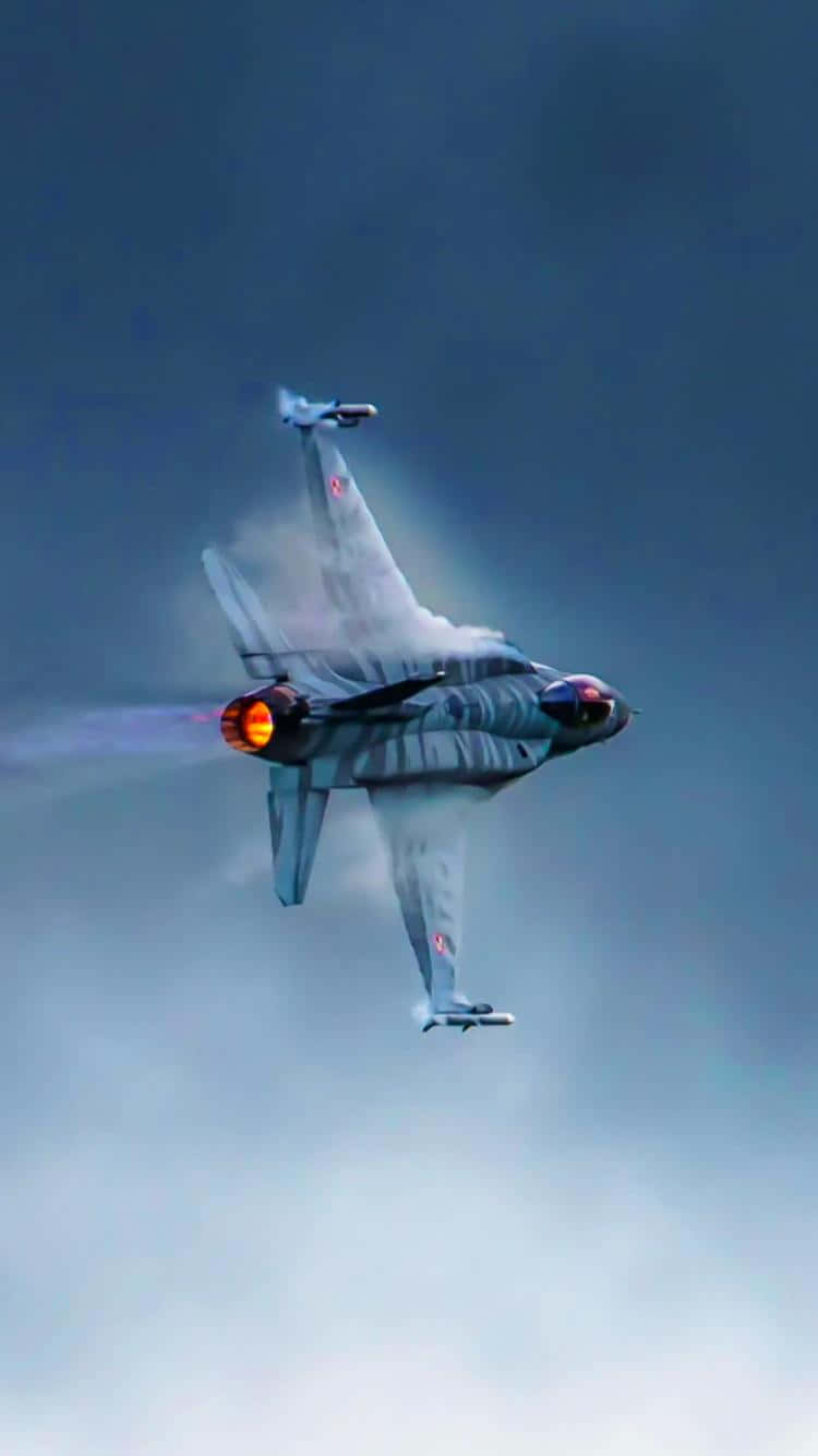 軍用戰鬥機Android巨無霸飛機背景 壁紙 — 一架灰色戰鬥機在陰雲密佈的天空中進行極限空中機動，尾焰發光。