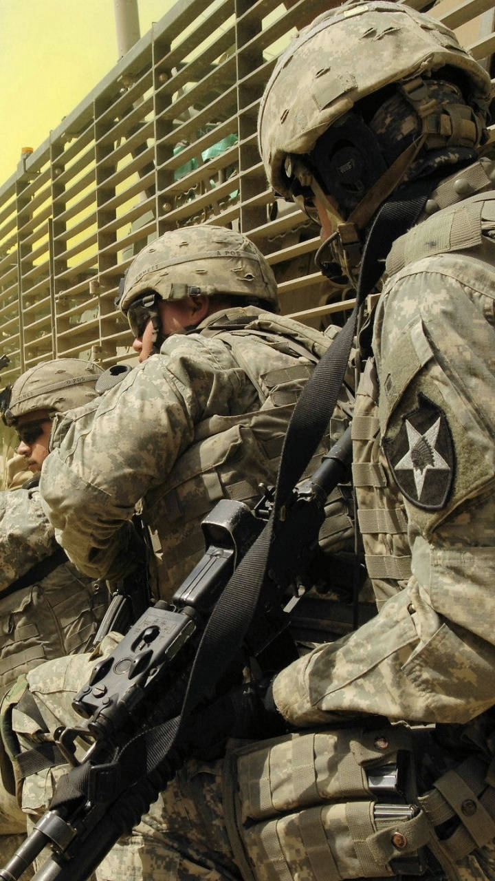 身穿作戰裝備的士兵在塵土飛揚的城市環境中持步槍保持警覺。
