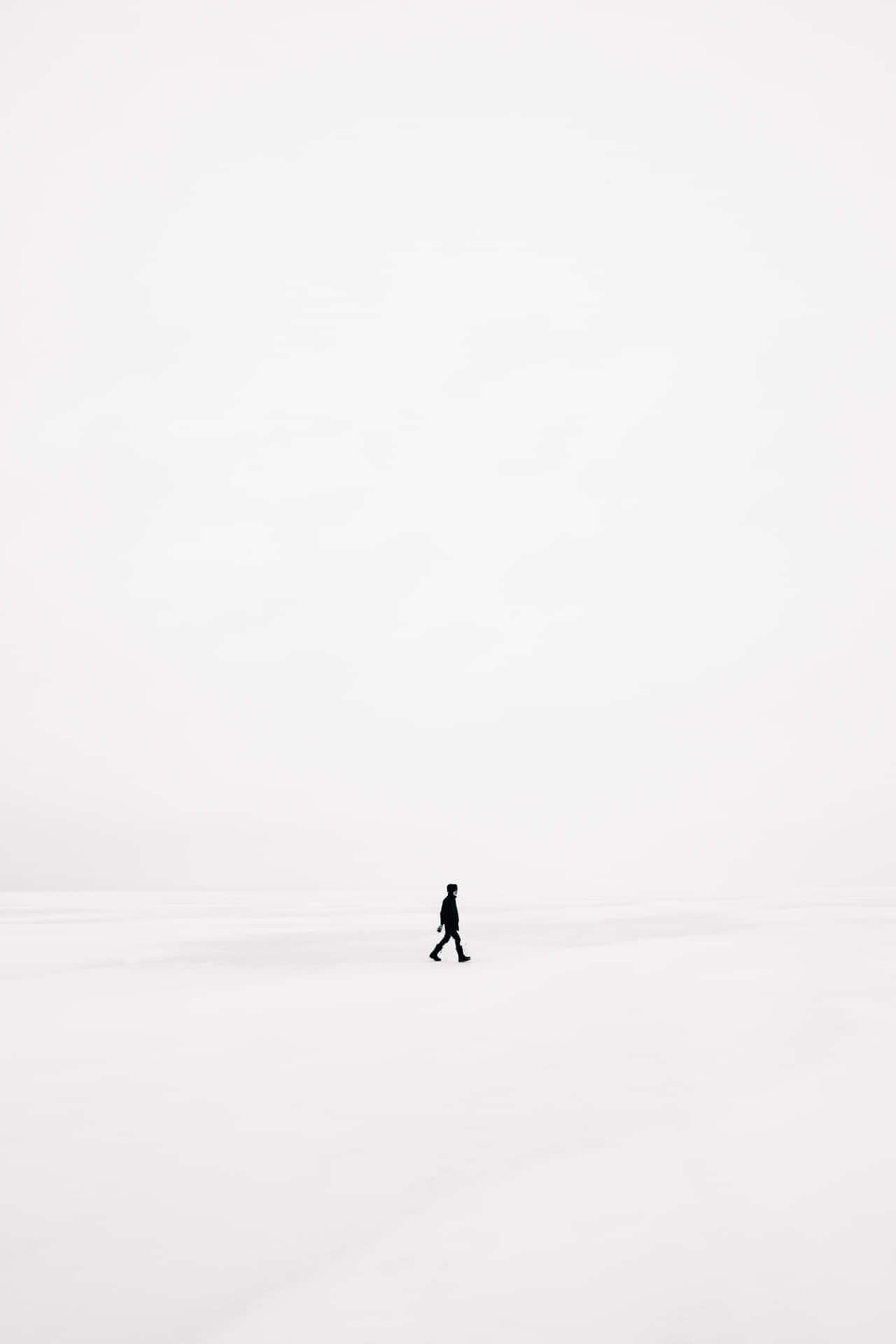 一個人獨自走過廣闊的雪景。
