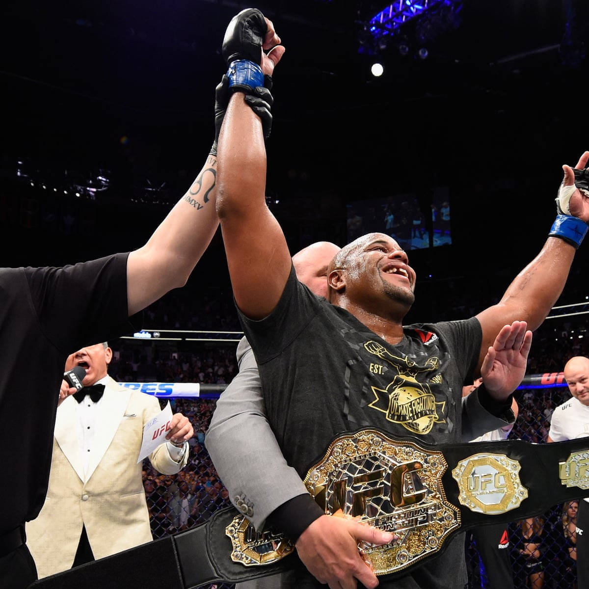 輕重量級冠軍丹尼爾·科爾米爾 UFC 226 壁紙 — 一位勝利的UFC拳手在八角籠中慶祝勝利，官員們舉起他的手臂，手持他的冠軍腰帶。