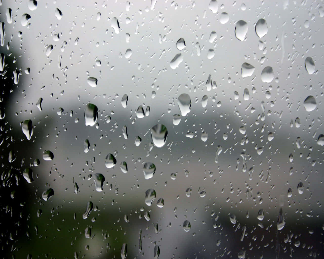 輕霧鏡面映藍天 壁紙 — 雨滴依附在玻璃窗上，模糊了外面灰色的城市景象。
