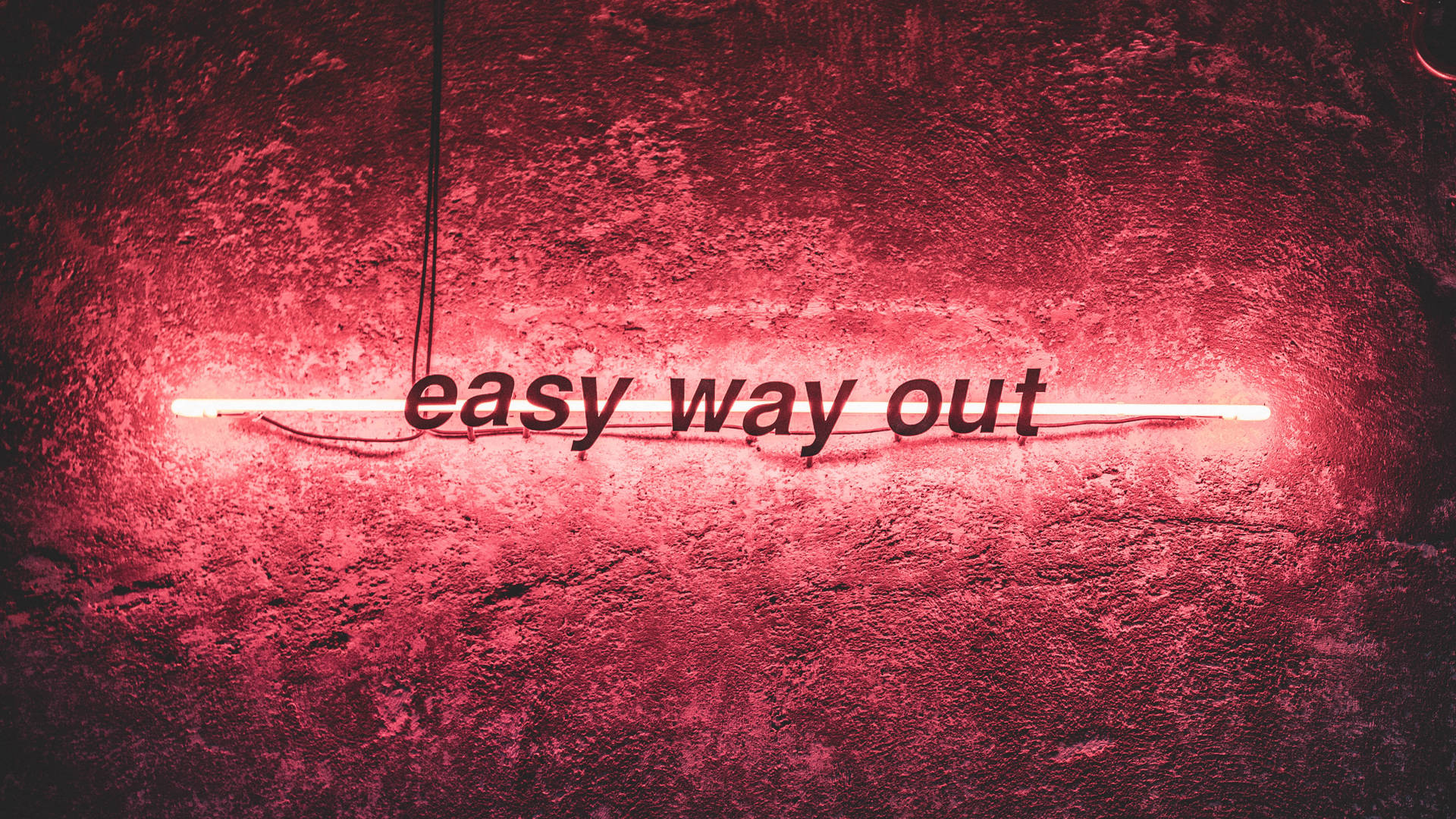 紅色霓虹燈牌，上面寫著 easy way out，位於紋理牆上。