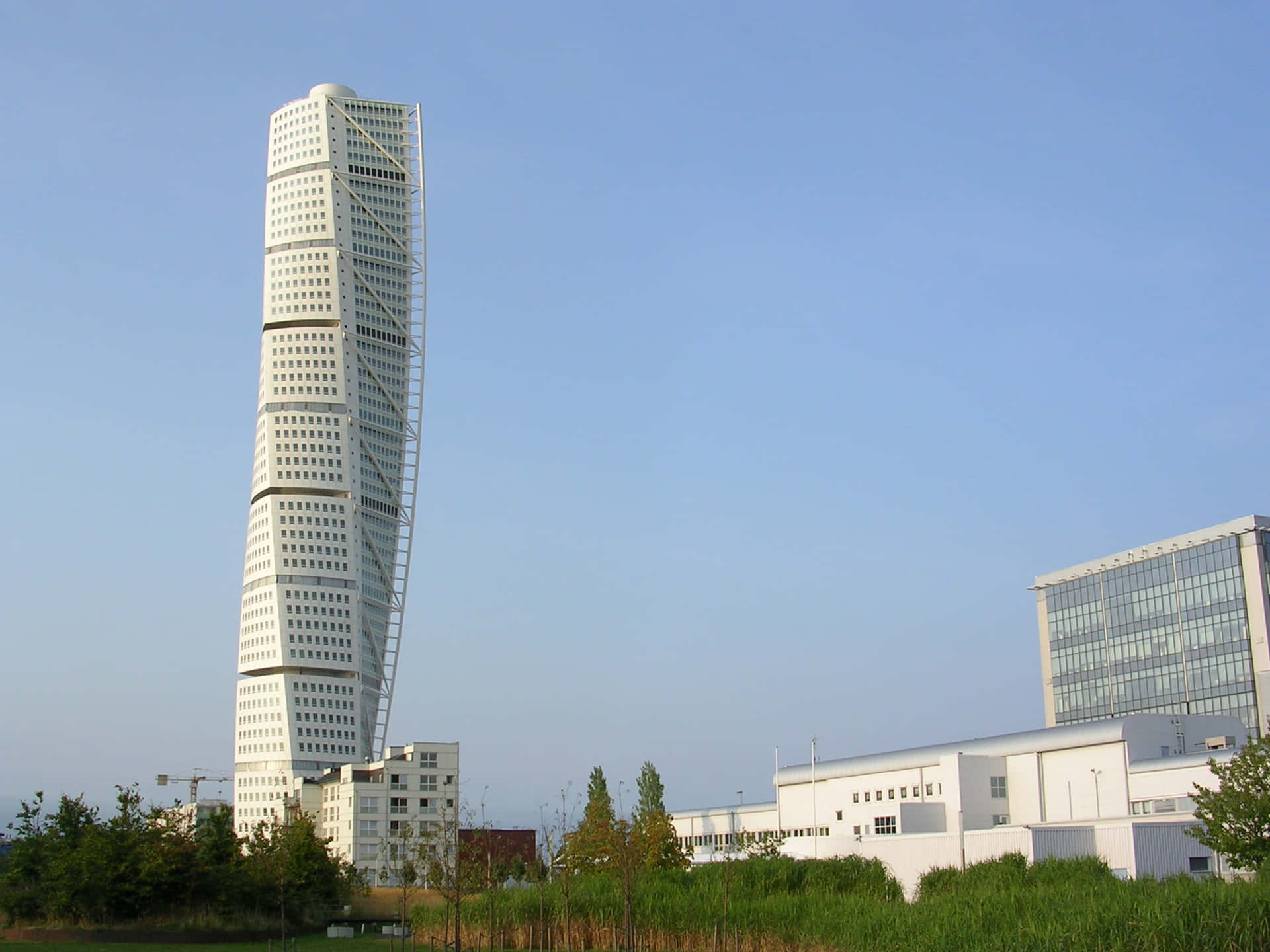 城市環境中的扭曲白色摩天大樓，背景是清澈的藍天和周圍的建築。