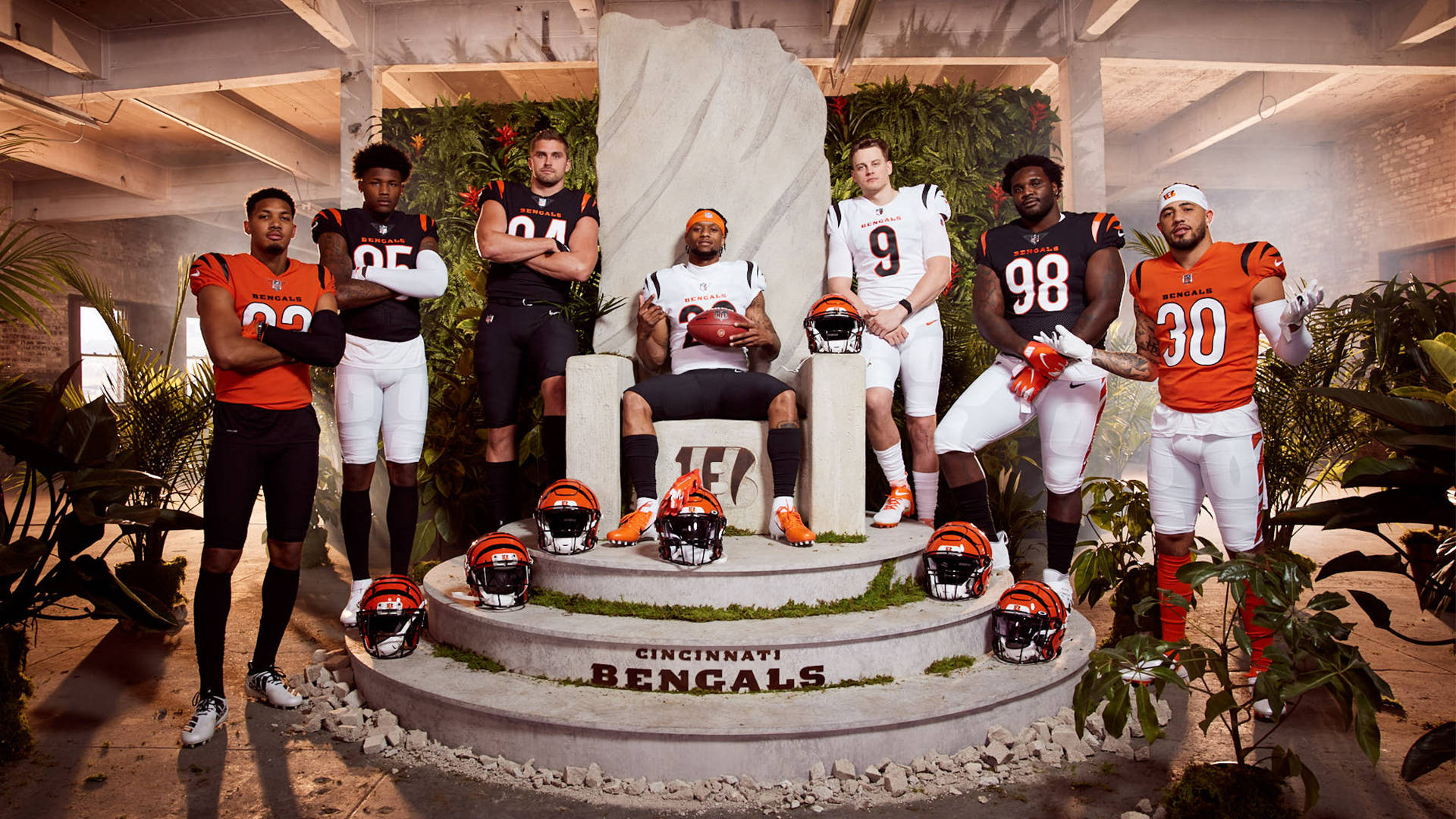 辛辛那提猛虎隊球員名單 壁紙 — 辛辛那提猛虎隊的足球員身穿橙色和黑色制服，戲劇性地圍繞著一個石頭王座，頭盔放在腳邊。