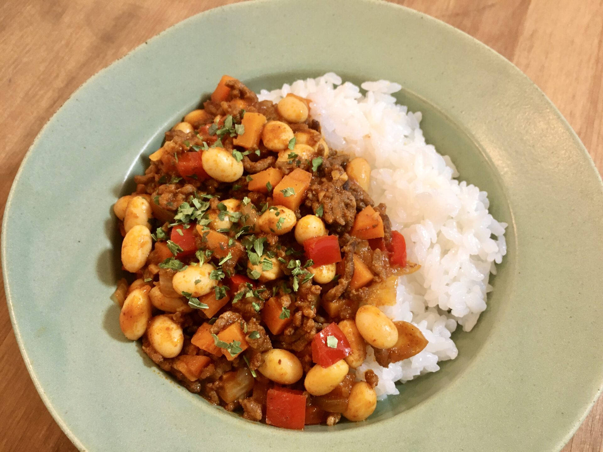 一碗豆肉燉菜配米飯放在木桌上。