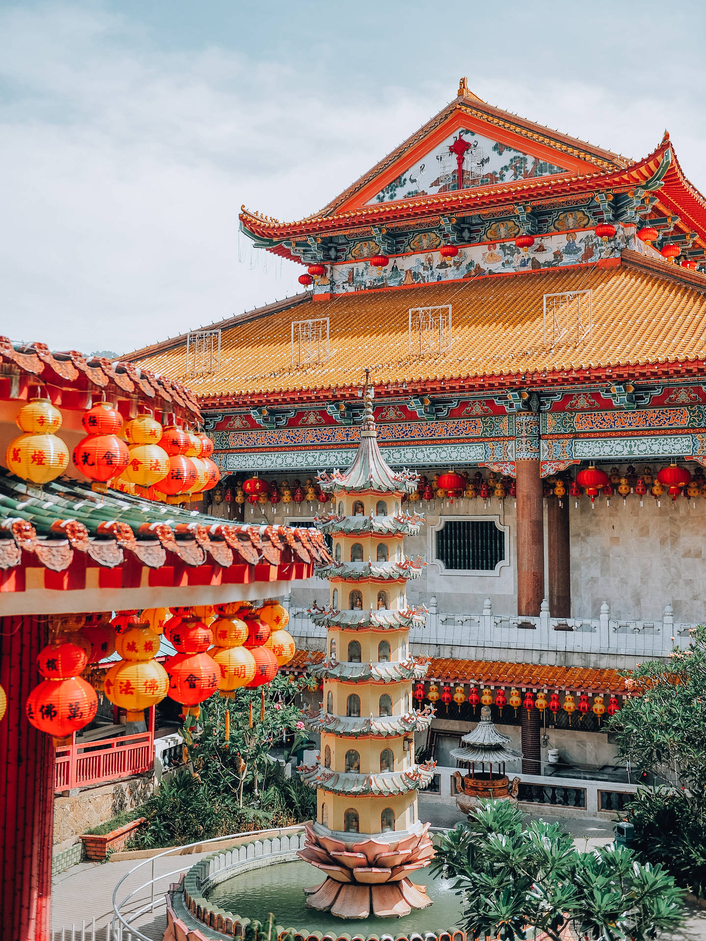 色彩繽紛的中國寺廟庭院，有紅色燈籠和中央的寶塔噴泉。