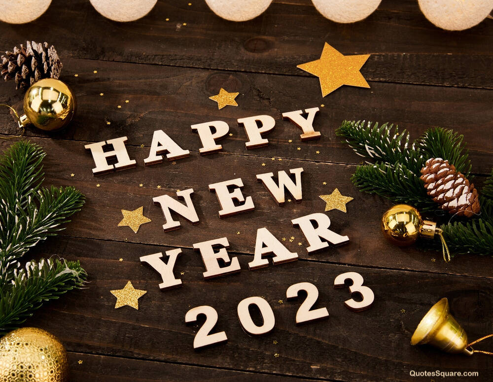 Happy New Year 2023 文字被松樹枝、松果和金飾環繞在深色木板上。