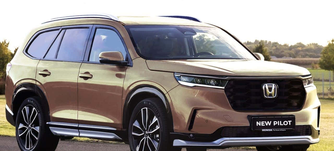 迎接2023，駕馭時尚Honda Pilot 壁紙 — 一輛時尚的金色本田Pilot SUV在明亮的日光下停泊在碎石路上，背景有樹木和開闊的田野。