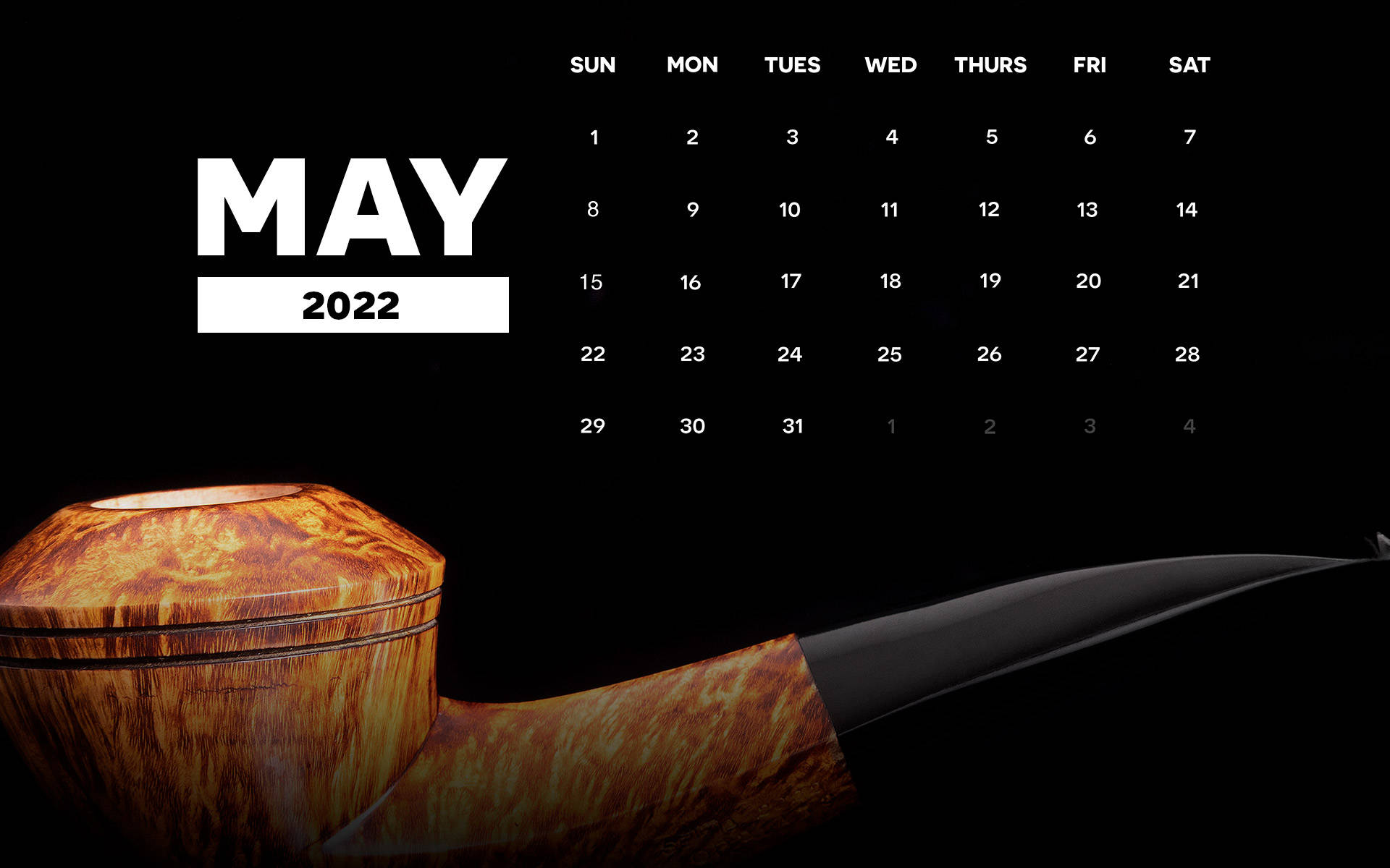 一個帶黑色煙嘴的木煙斗放在黑色背景的2022年5月日曆前。
