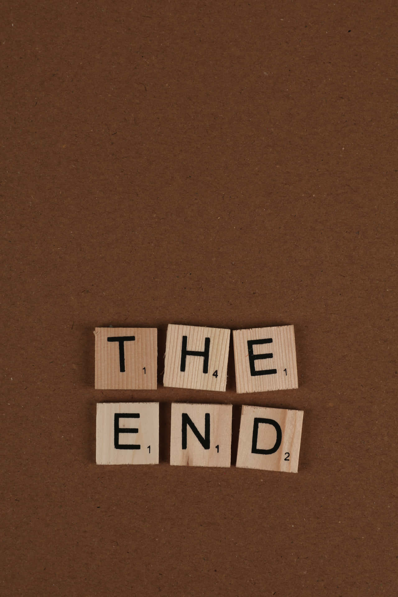 木製 Scrabble 字塊在棕色背景上拼出 the end
