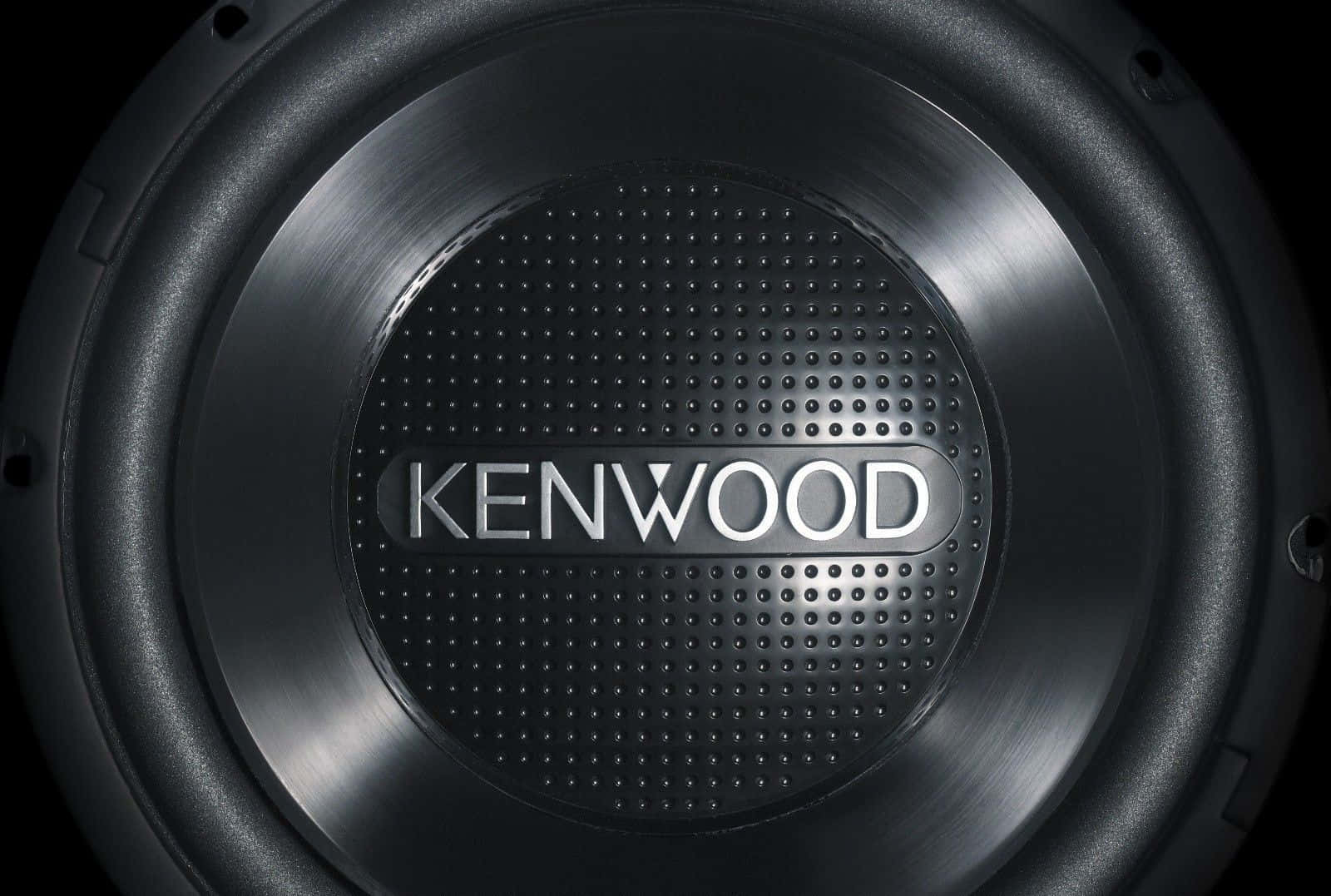 Car Audio 桌布 壁紙 — 近距離拍攝一款時尚黑色Kenwood超低音揚聲器，具有金屬質感飾面和穿孔網格，在攝影棚燈光下展示。