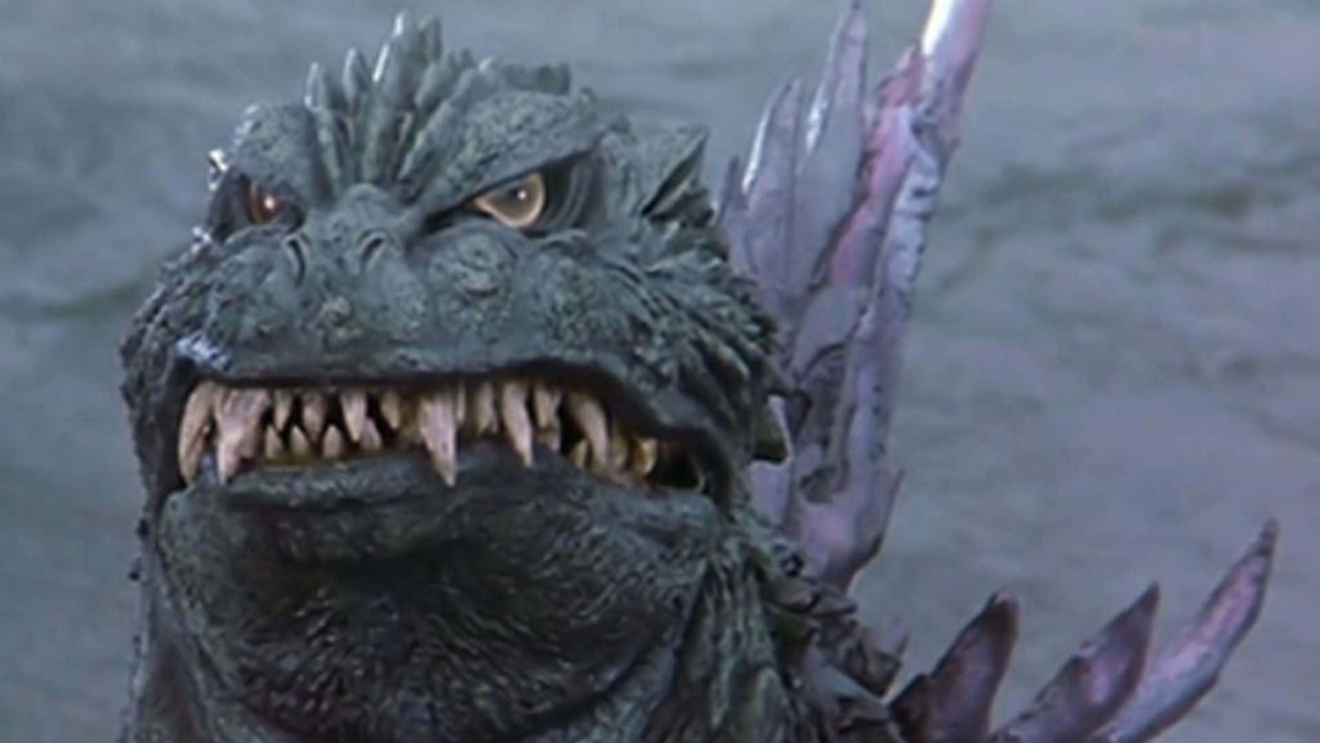 Godzilla 2000 桌布 壁紙 — 近距離拍攝一隻咆哮的哥斯拉，背上有尖刺，露出鋒利牙齒，從渾濁的水中冒出。
