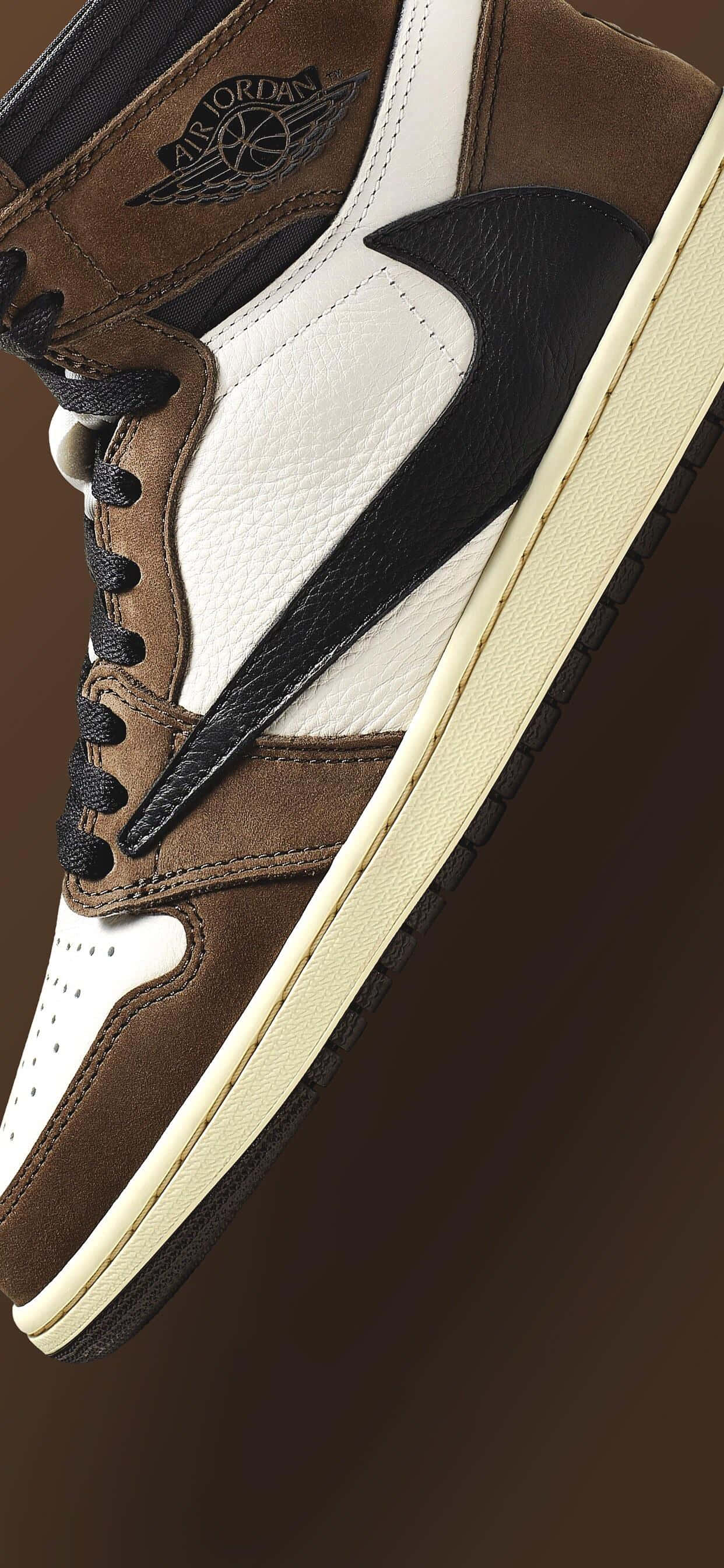 Travis Scott Jordan 1 桌布 壁紙 — 近距離拍攝一雙棕色、白色和黑色的Air Jordan運動鞋，搭配奶油色鞋底，背景為深棕色漸變色。