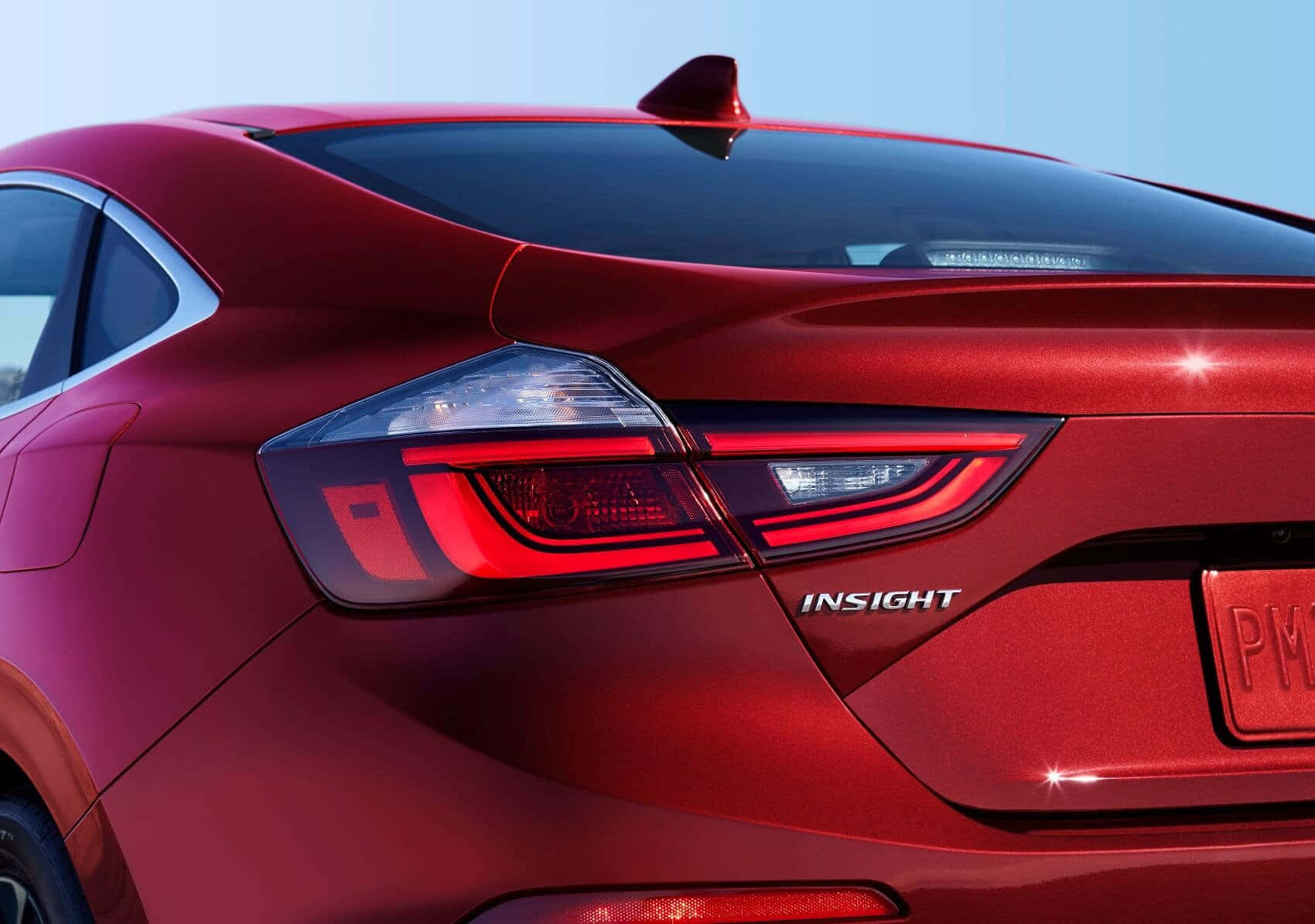 Honda Insight 桌布 壁紙 — 近距離拍攝亮面紅色本田 Insight 的車尾，展現流線型尾燈和 'INSIGHT' 徽章，背景是清澈的藍天。