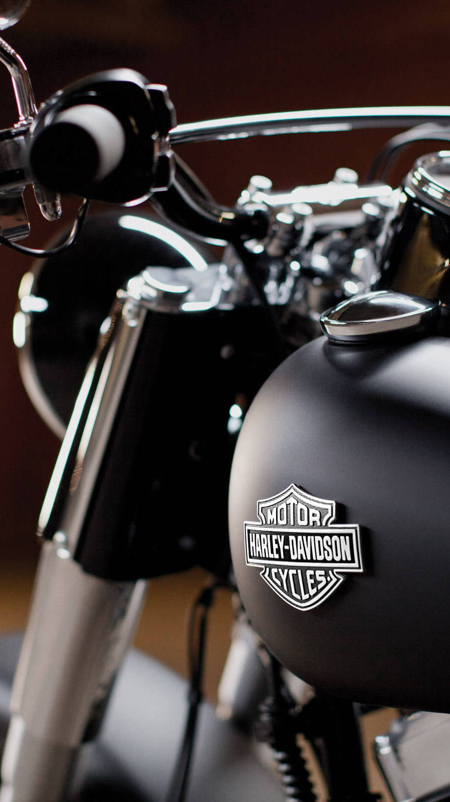 哈雷戴維森 桌布 壁紙 — 近距離拍攝啞光黑色Harley-Davidson電單車油箱，配以鍍鉻把手和引擎細節，在柔和的工作室燈光下。
