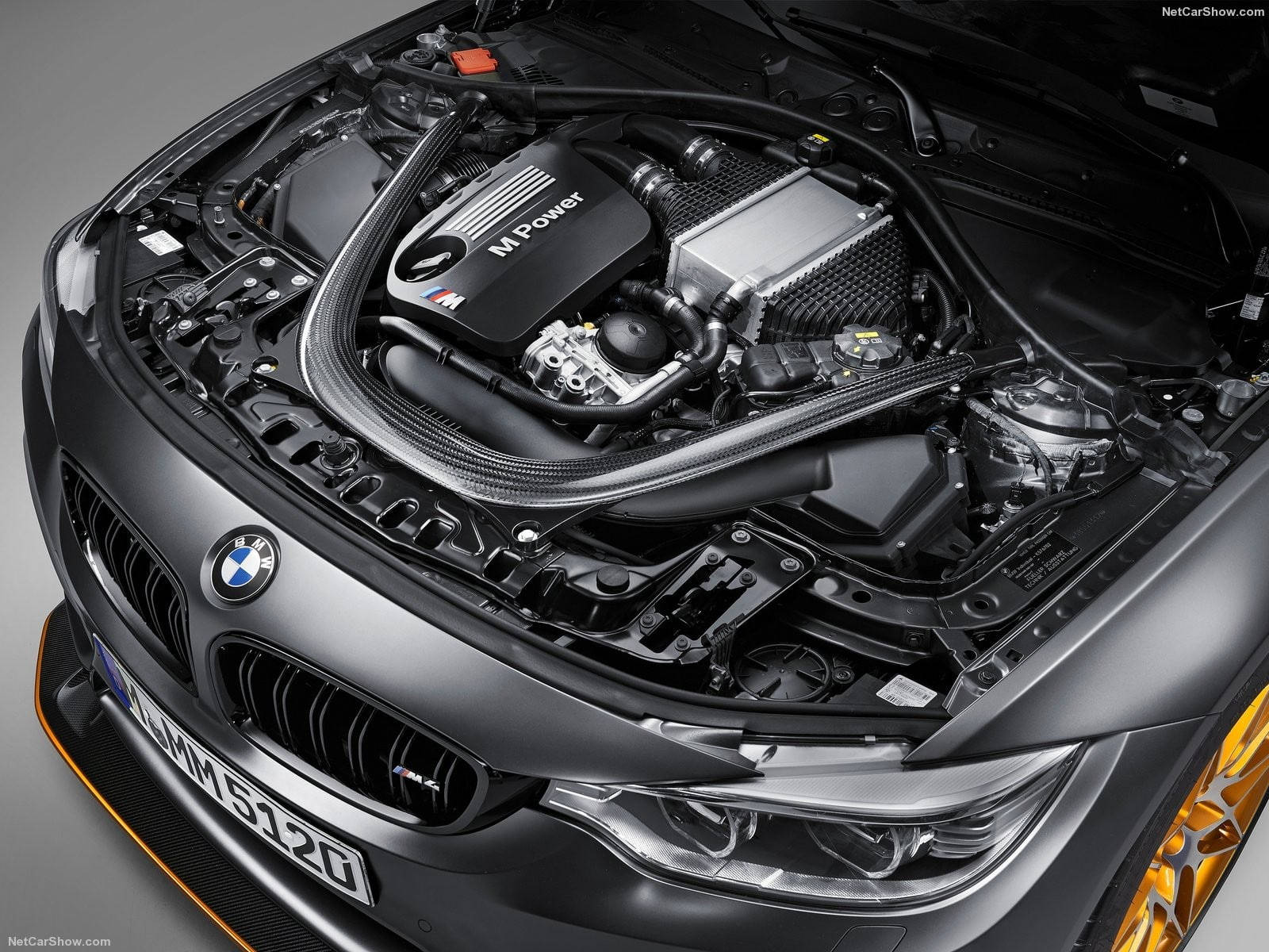 Sports Car 桌布 壁紙 — 近距離拍攝時尚黑色BMW M Power引擎艙，帶有橙色點綴和拋光金屬部件，在工作室燈光下。