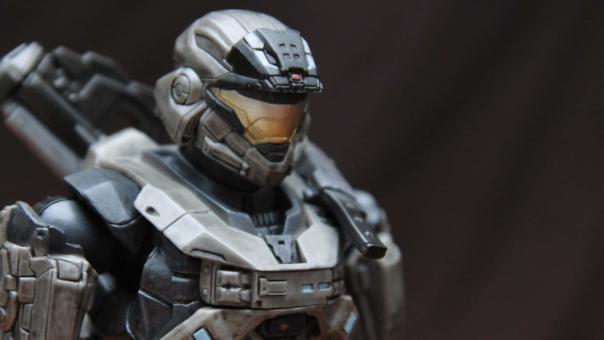 Noble Six 桌布 壁紙 — 近距離拍攝的詳細 Halo Spartan 動作人偶，身穿銀色和黑色裝甲，帶有發光的橙色面罩。