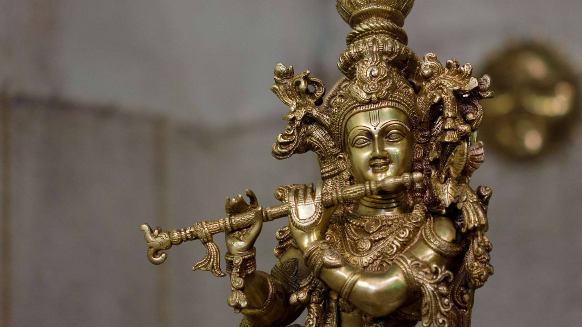 Krishna Flute 桌布 壁紙 — 近距離拍攝裝飾華麗的黃金主克里希納雕像，吹奏長笛，雕刻精細，表情寧靜。