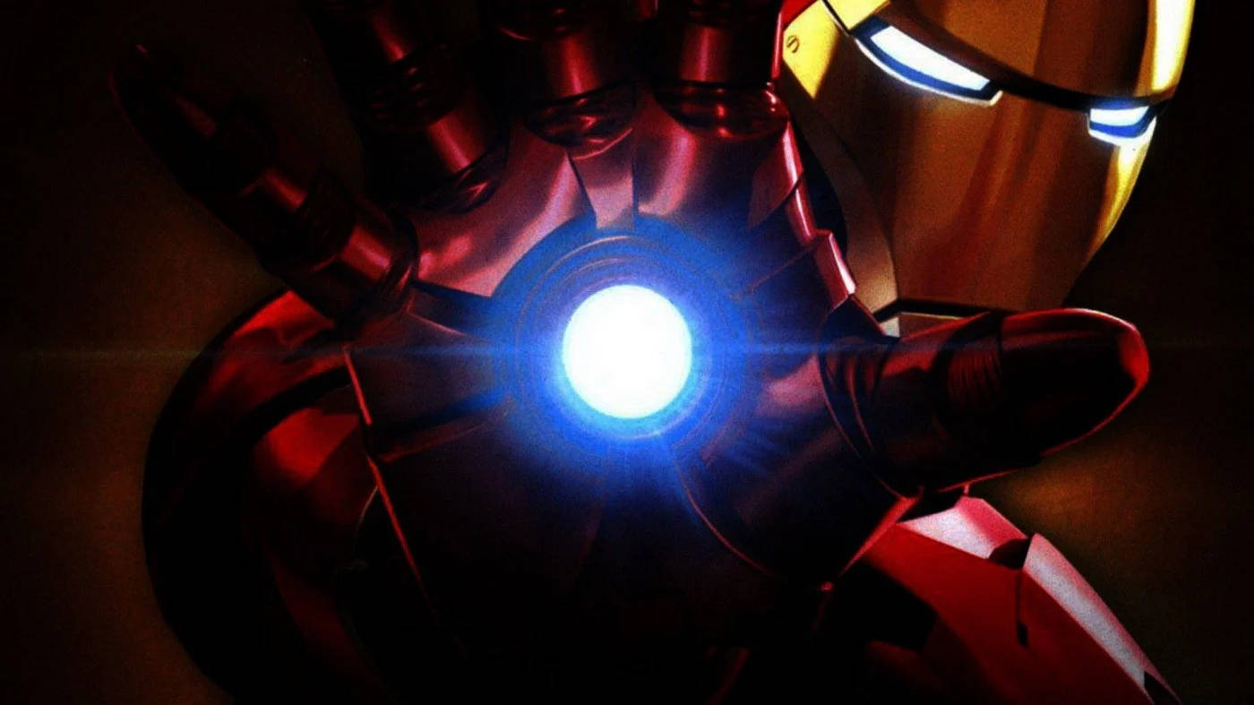 tony stark 桌布 壁紙 — 近距離拍攝鐵甲奇俠發光的弧形反應堆和頭盔，在黑暗背景下發出強烈藍光。
