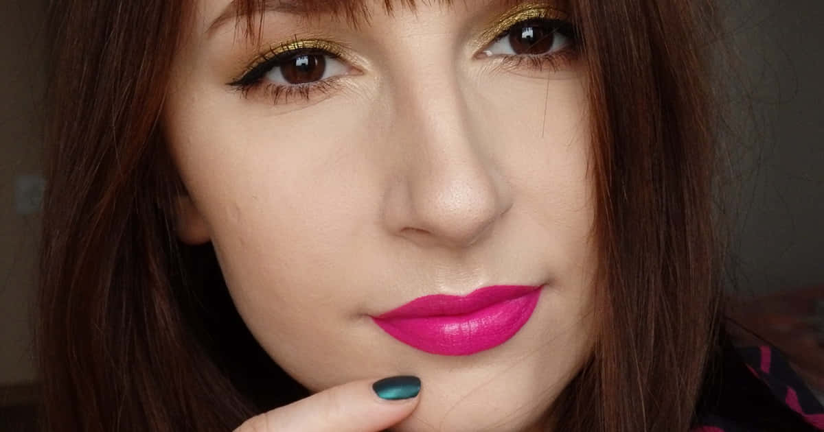 Spring Makeup 桌布 壁紙 — 近距離肖像，一位女性塗著大膽的粉紅唇色和閃爍的金色眼影，溫柔地凝視鏡頭。