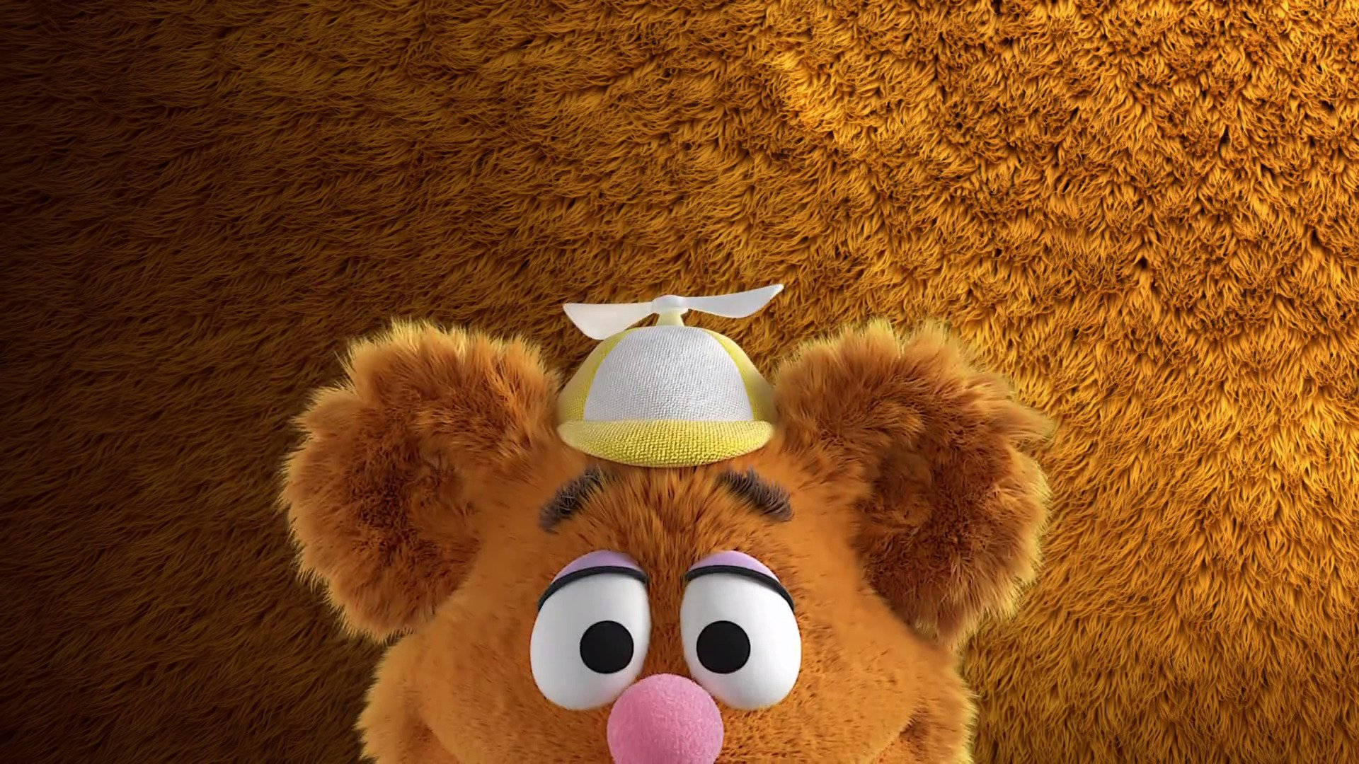 迪士尼《布偶娃娃》半臉佛奇 壁紙 — Fozzie Bear 戴住一頂細細嘅黃白色飛行員帽，背景係毛茸茸嘅啡色。