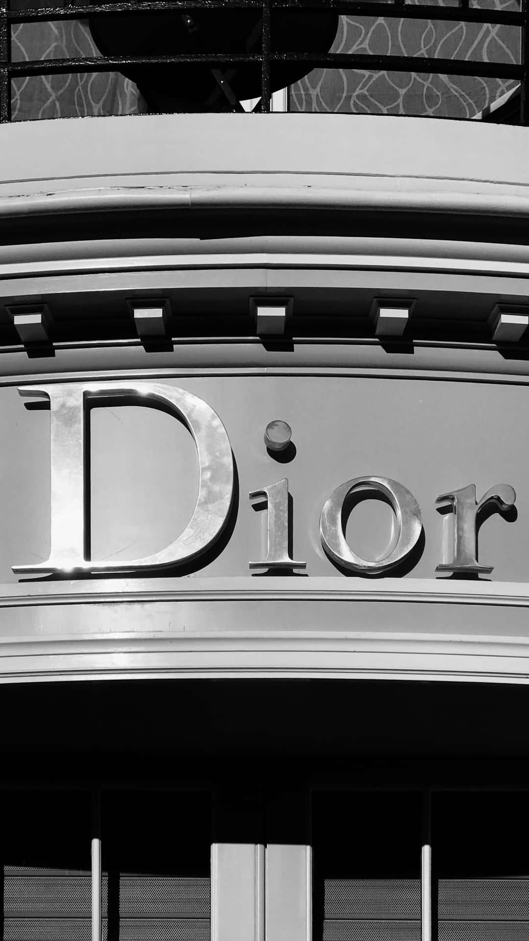 迪奧店舖招牌 壁紙 — Dior 標誌嘅黑白特寫，位於時尚建築物外牆，帶有幾何建築細節。