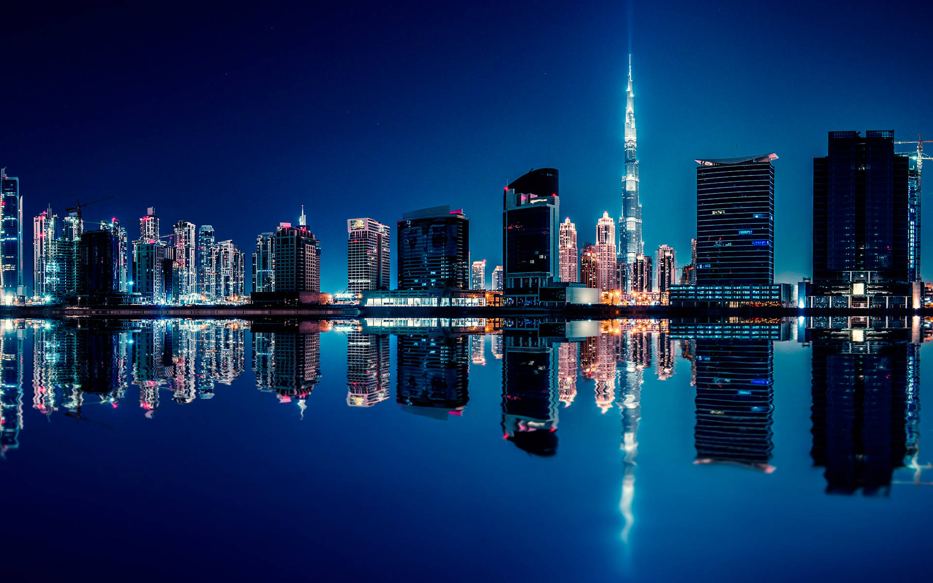 夜晚的杜拜天際線，摩天大樓倒映在平靜的水面上。
