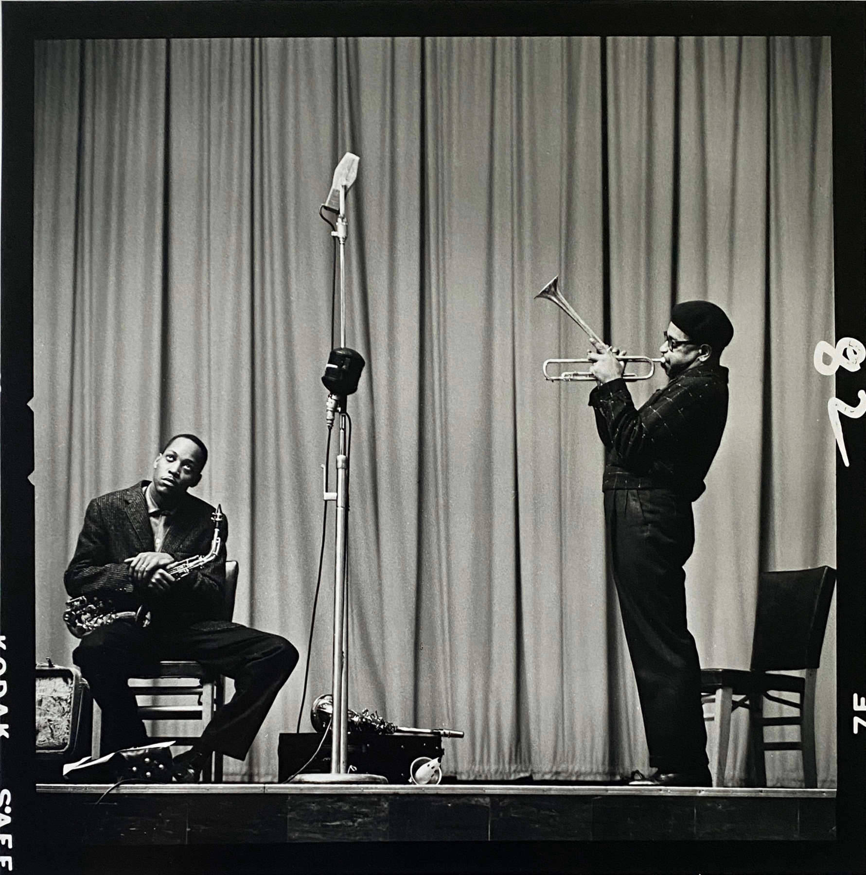 迪茲·吉萊斯皮於1948年紐約演出 壁紙 — 兩位爵士樂手在舞台上表演，一位坐著吹奏色士風，另一位站著吹奏小號，在復古聚光燈下。