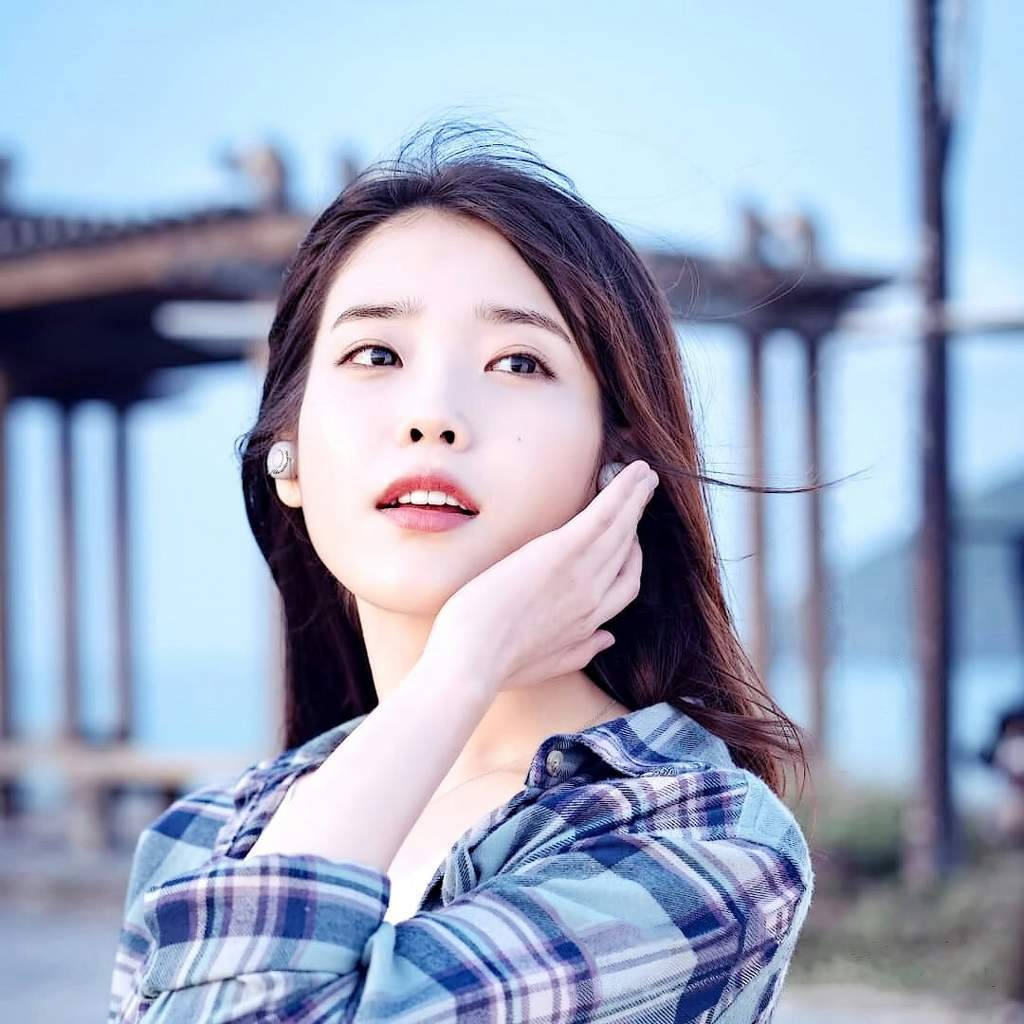 年輕女性穿著格仔衫在明亮的日子裡於戶外觸摸臉頰。