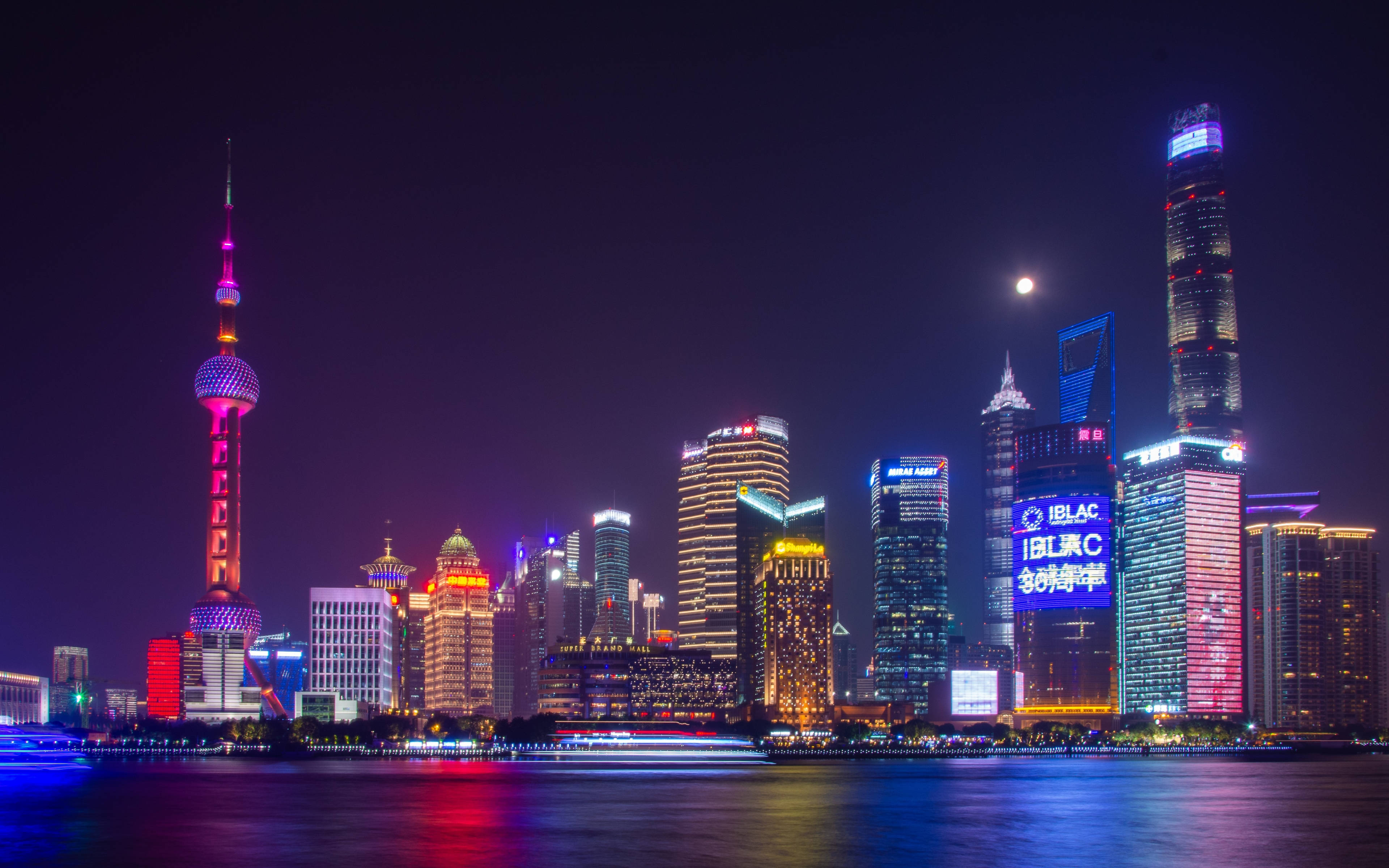 迷人夜景城市風光桌面 壁紙 — 上海令人目眩神迷的夜景天際線，閃爍的摩天大樓和標誌性的東方明珠塔在月光下的黃浦江上倒映。