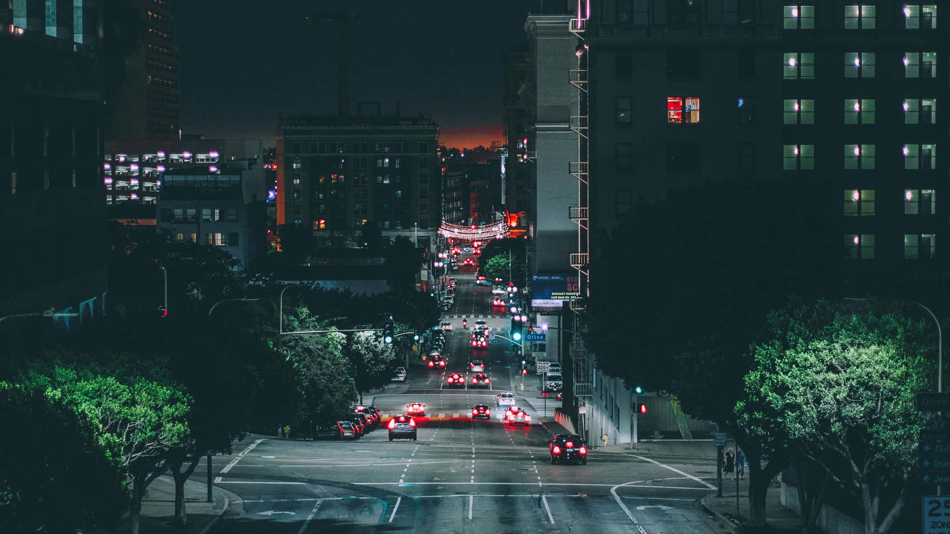 夜晚的城市街道，在暮色天空下，紅色尾燈和燈火通明的建築物。