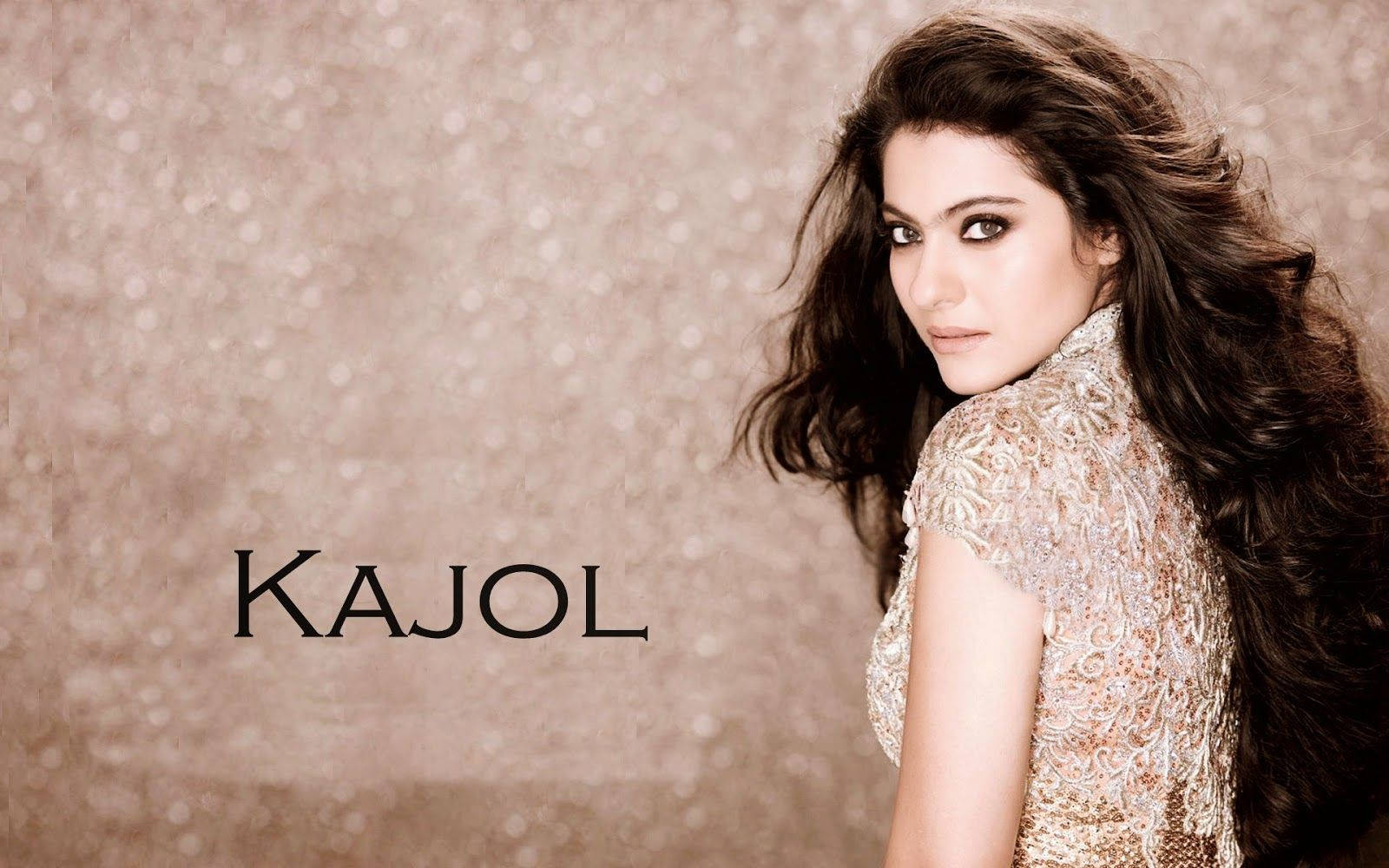 迷人寶萊塢女星 Kajol Devgn 壁紙 — 一位長黑髮的迷人女性穿著閃閃發光的金色連衣裙，站在有紋理的米色背景前，她的名字以粗體文字呈現。
