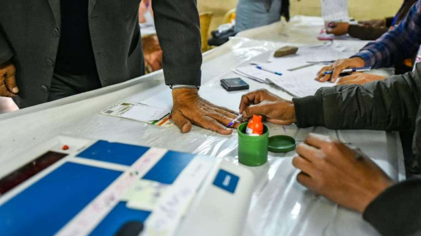 在投票站，工作人員在附近為選民手指沾墨。