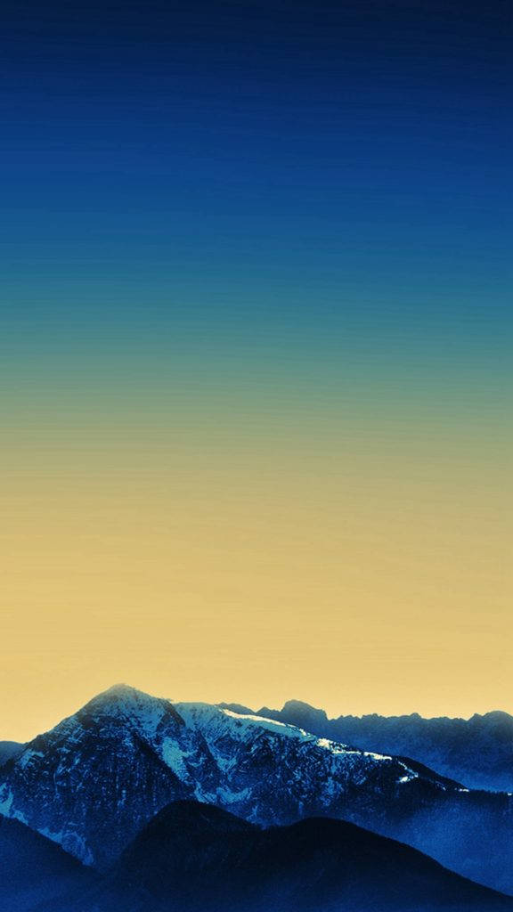 迷人山景藝術 iPhone 壁紙 — 積雪的山峰在日落時分從深藍色漸變到金黃色的天空襯托下聳立。