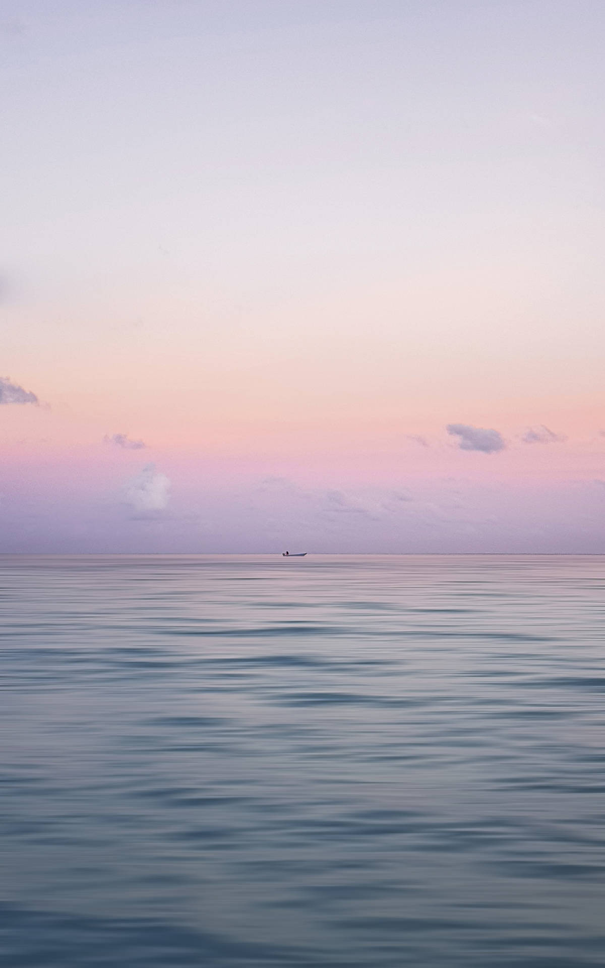 迷人海洋黃昏——藍與金的對比 壁紙 — 一艘孤獨的小船在平靜的海面上漂流，天空是柔和的粉紅色和薰衣草色的黃昏。