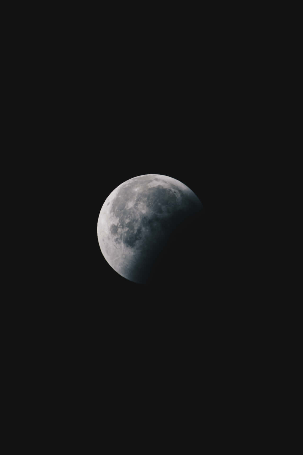 迷人滿月iPhone背景 壁紙 — 一彎新月，帶有可見的隕石坑和月海，懸掛在深黑色的天空中。