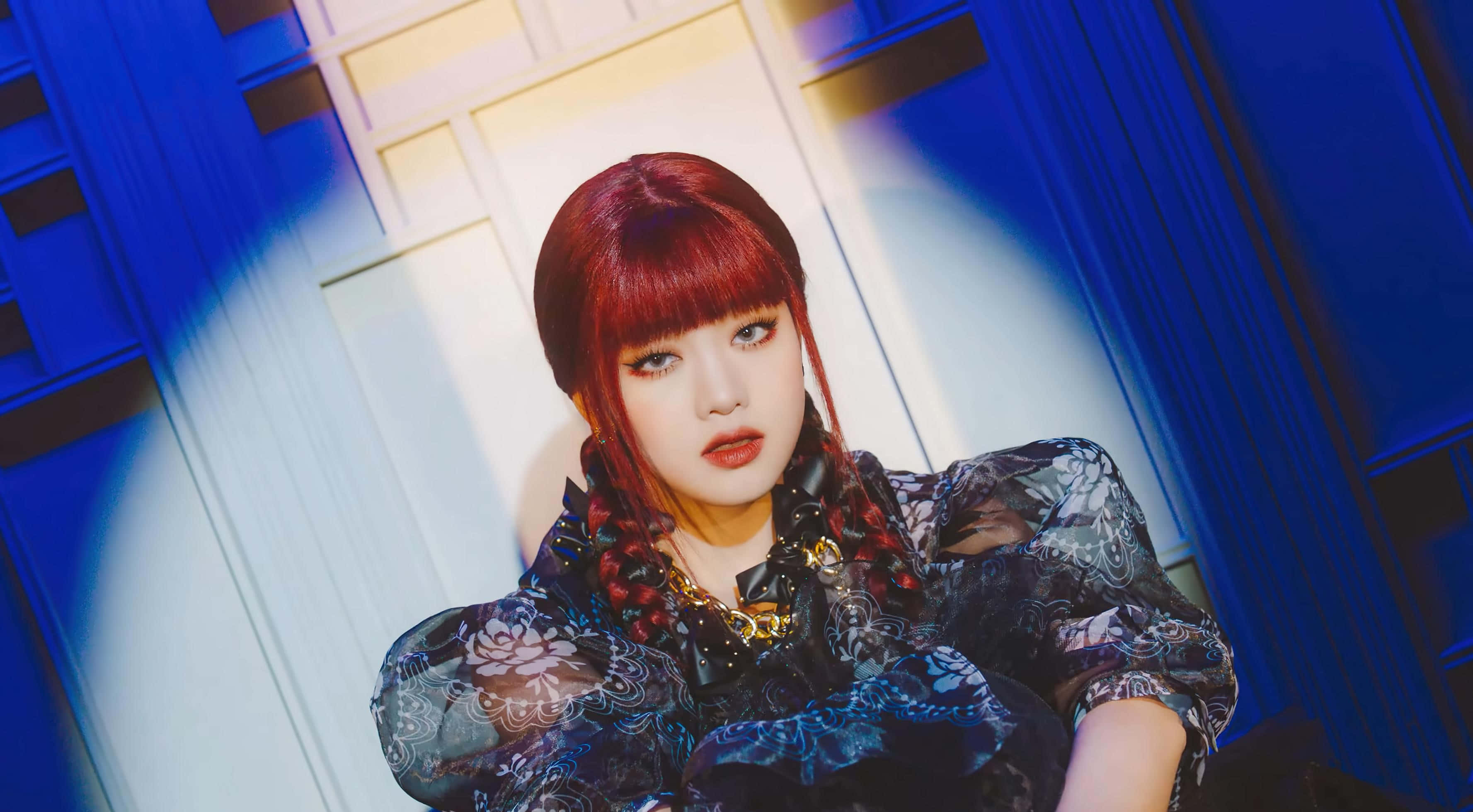 迷人的 K-pop 偶像以迷人姿態吸睛 壁紙 — 一位紅髮辮子女性穿著深色花卉連衣裙，在戲劇性的藍白燈光下。