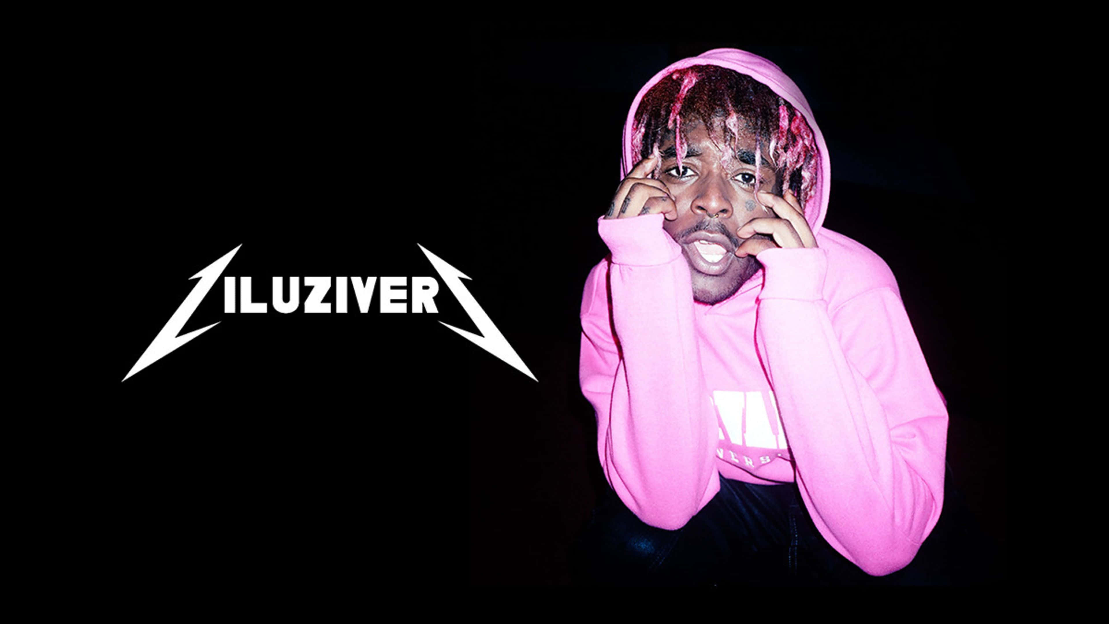 迷人的 Lil Uzi Vert 4K 桌面主題 壁紙 — 一名穿著粉紅色連帽衫、粉紅色頭髮的男子在黑色背景前，在白色「ILUZIVER」標誌旁邊擺姿勢。