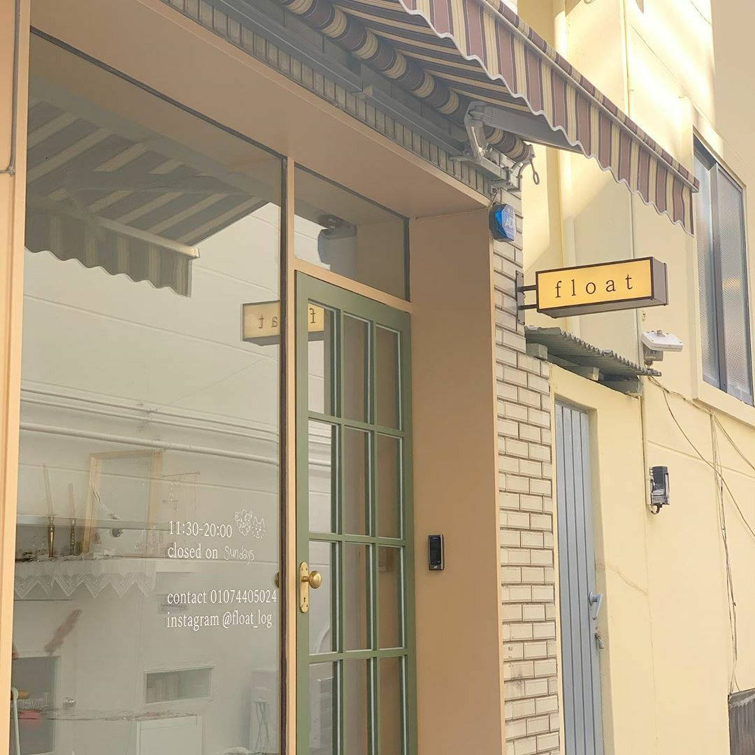 Pinterest Aesthetic 桌布 壁紙 — 迷人的店面，在溫暖陽光下設有條紋遮陽篷和綠色邊框玻璃門。