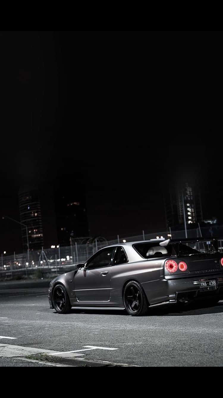 灰色跑車帶紅色尾燈停在夜晚潮濕的城市街道上。