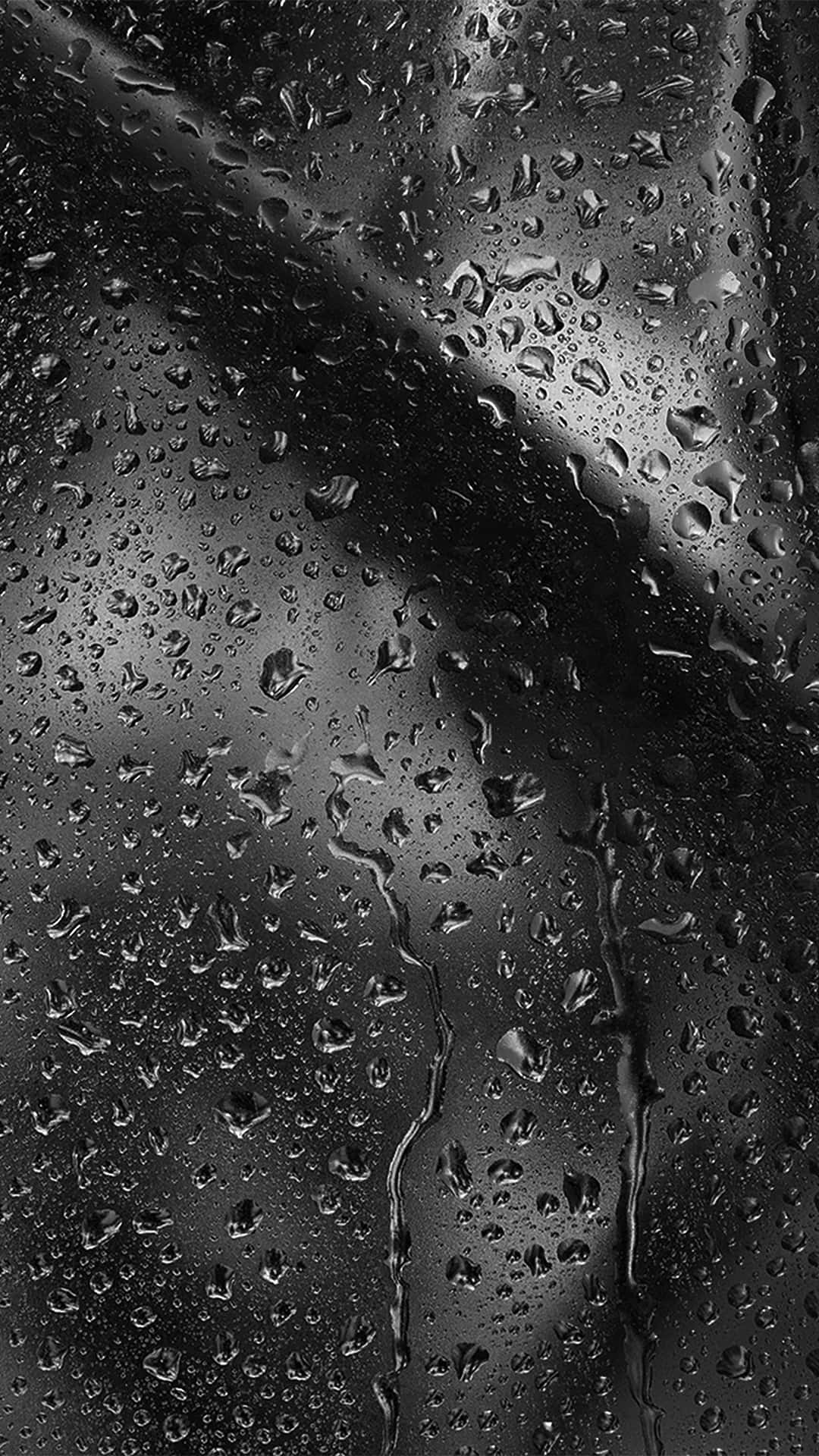 夜晚雨滴沿深色玻璃窗滑落