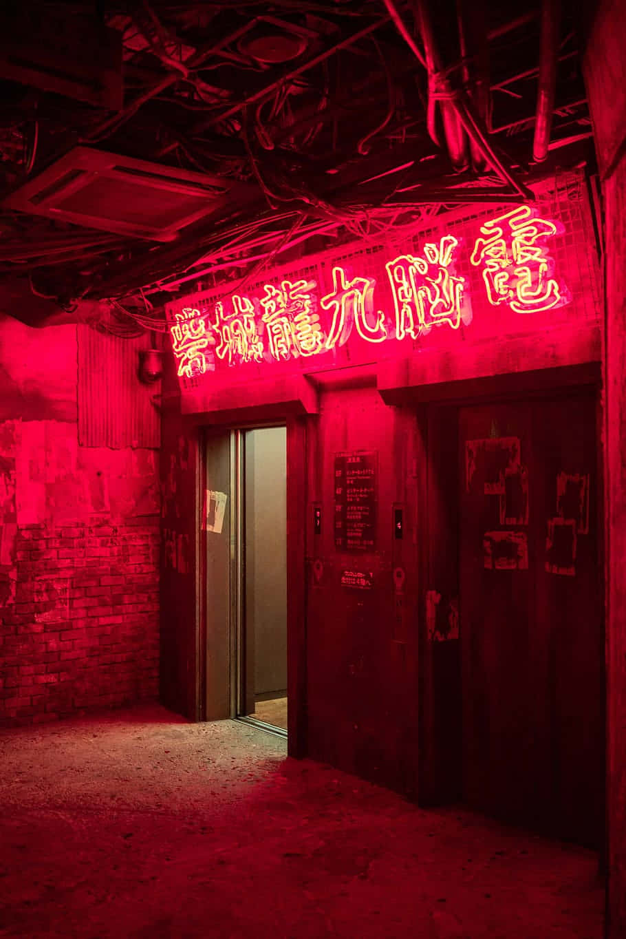 迷人紅色美學 壁紙 — 一條昏暗的城市小巷，被一個發光的中文招牌上的強烈紅色霓虹燈光照射在風化的門上。