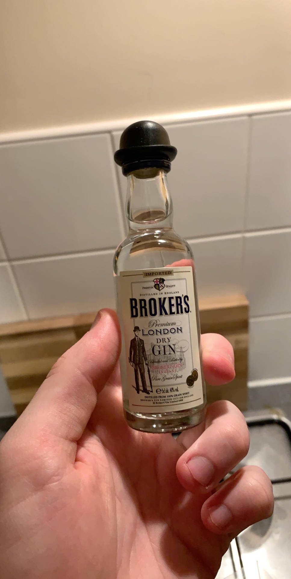 手在廚房裡拿著一個小琴酒瓶。