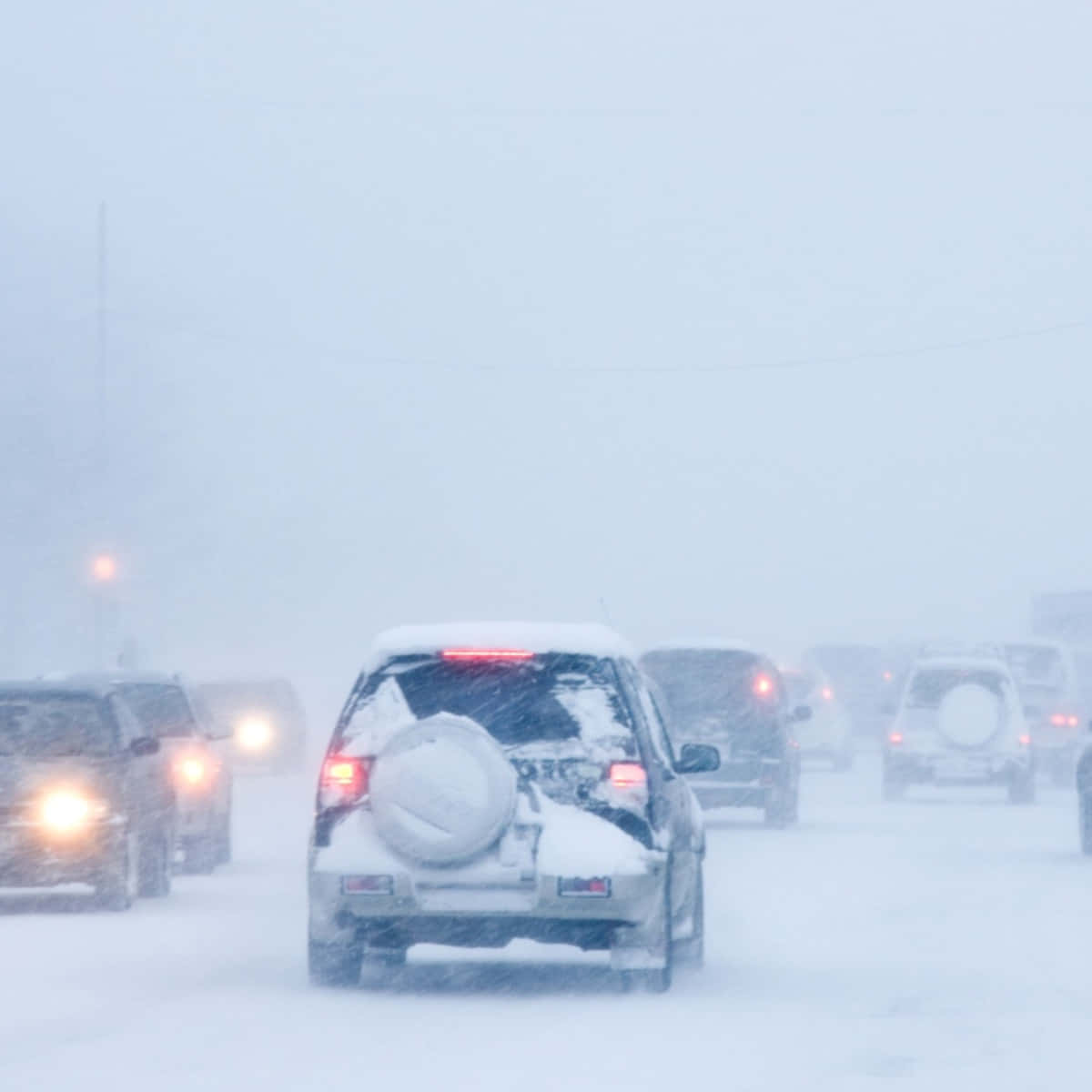 「迷失於暴雪之中」 壁紙 — 汽車在暴風雪中行駛，車頭燈穿透結冰道路上的白茫茫暴風雪。