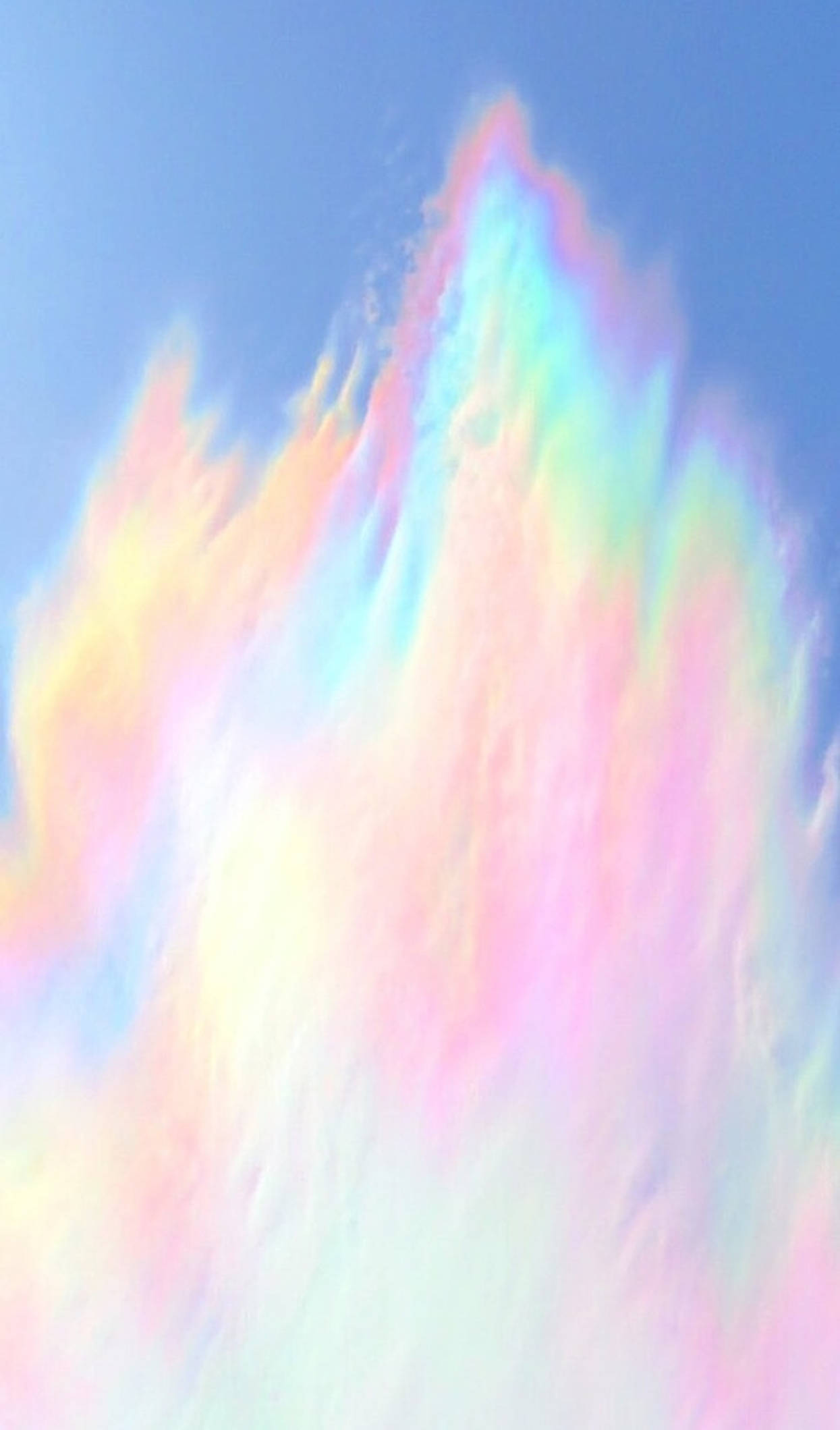 迷幻柔和彩虹色調 壁紙 — 充滿活力的彩虹色雲層在柔和的粉彩漸變中，在清澈的藍天中向上爆發。
