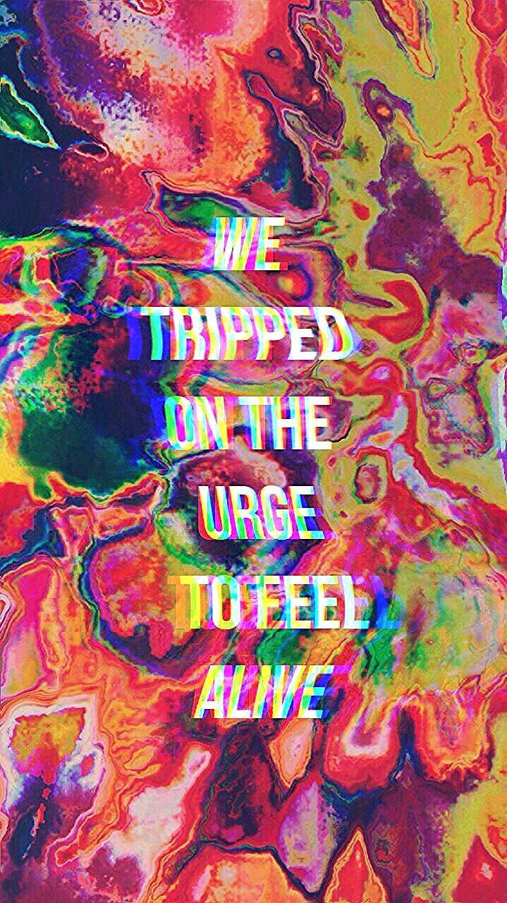 迷幻金句 壁紙 — 充滿活力的迷幻霓虹色漩渦形成一個迷幻的抽象背景，帶有發光的故障文字，寫著 'WE TRIPPED ON THE URGE TO FEEL ALIVE'。
