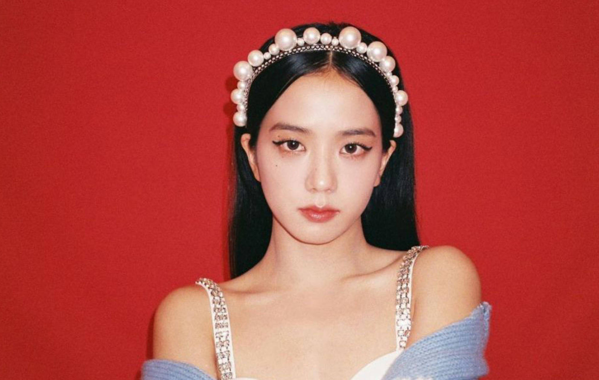 逃離公主Jisoo 壁紙 — 一位深色頭髮的年輕女性戴著珍珠頭帶，穿著藍色露肩上衣，背景是鮮明的紅色。